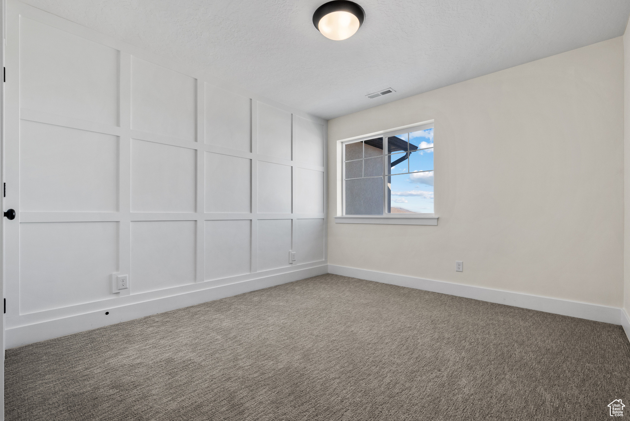 Carpeted empty room with a textured ceiling