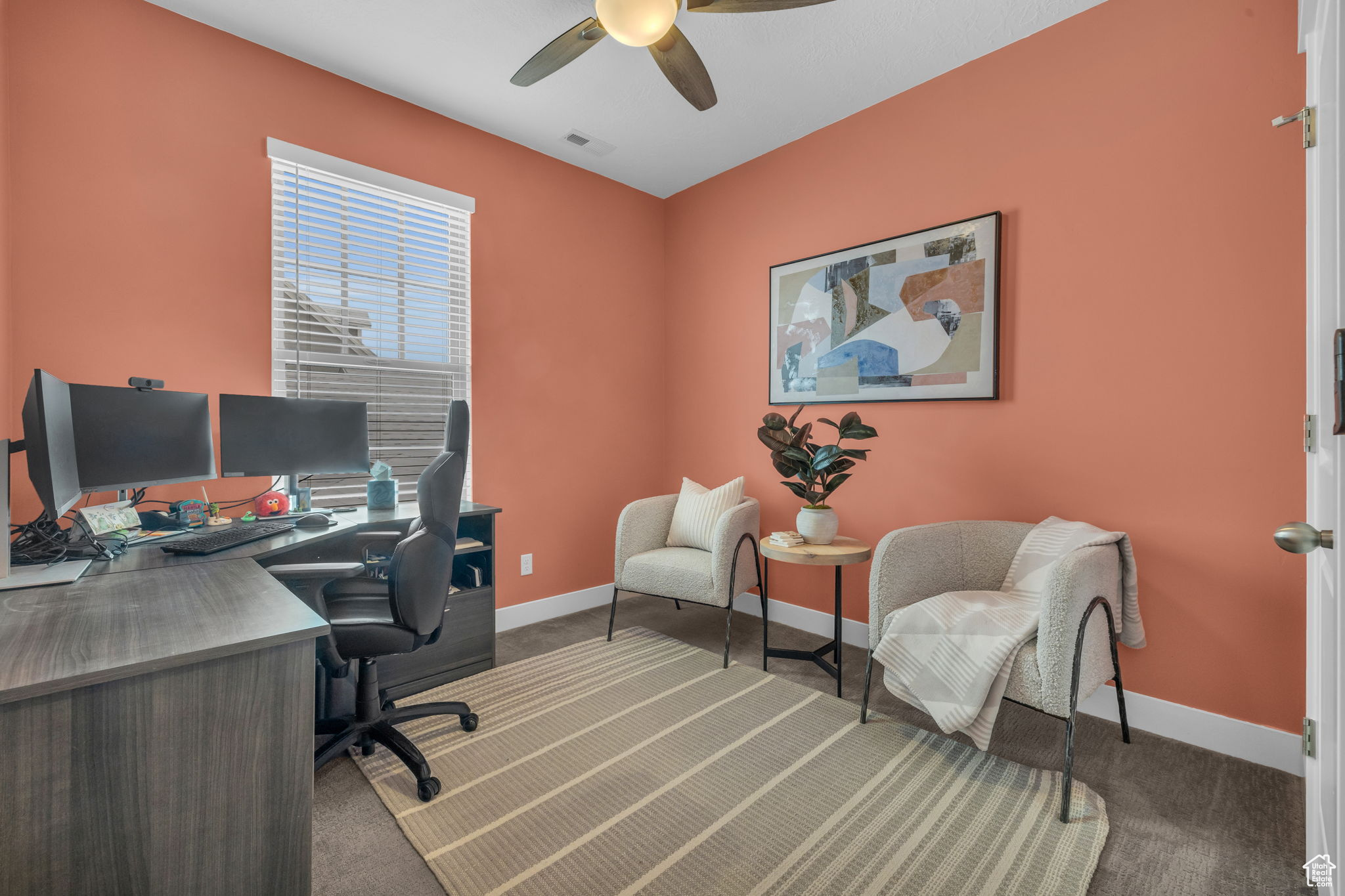 Carpeted office featuring ceiling fan