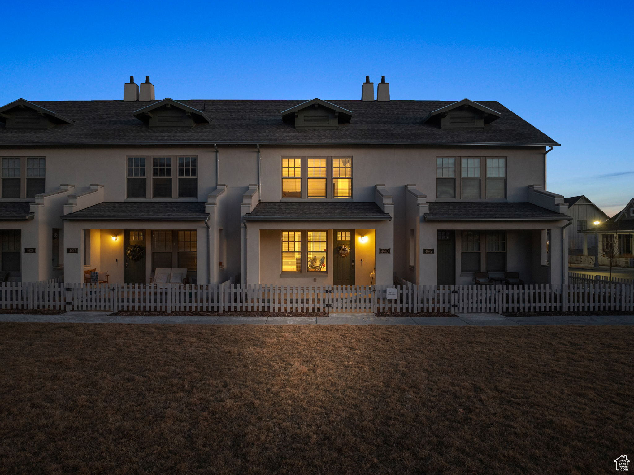 Back house at dusk featuring a lawn