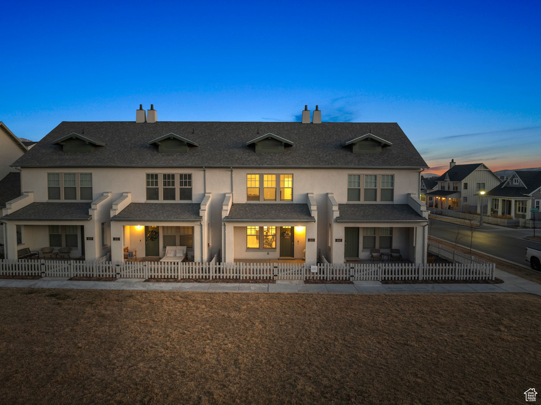 Back house at dusk featuring a patio and a yard