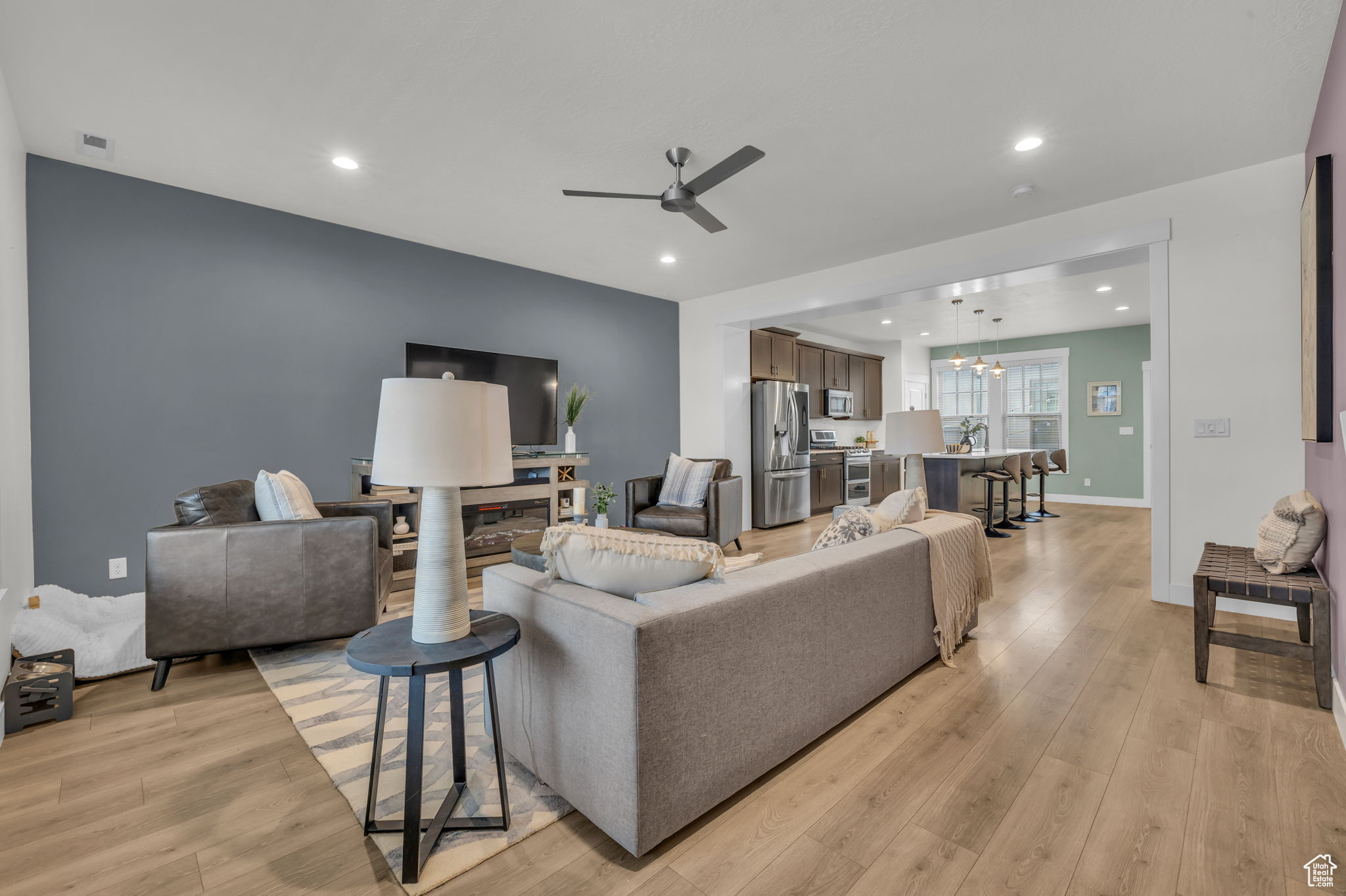 Living room featuring sink, ceiling fan with notable chandelier, and light wood-type flooring