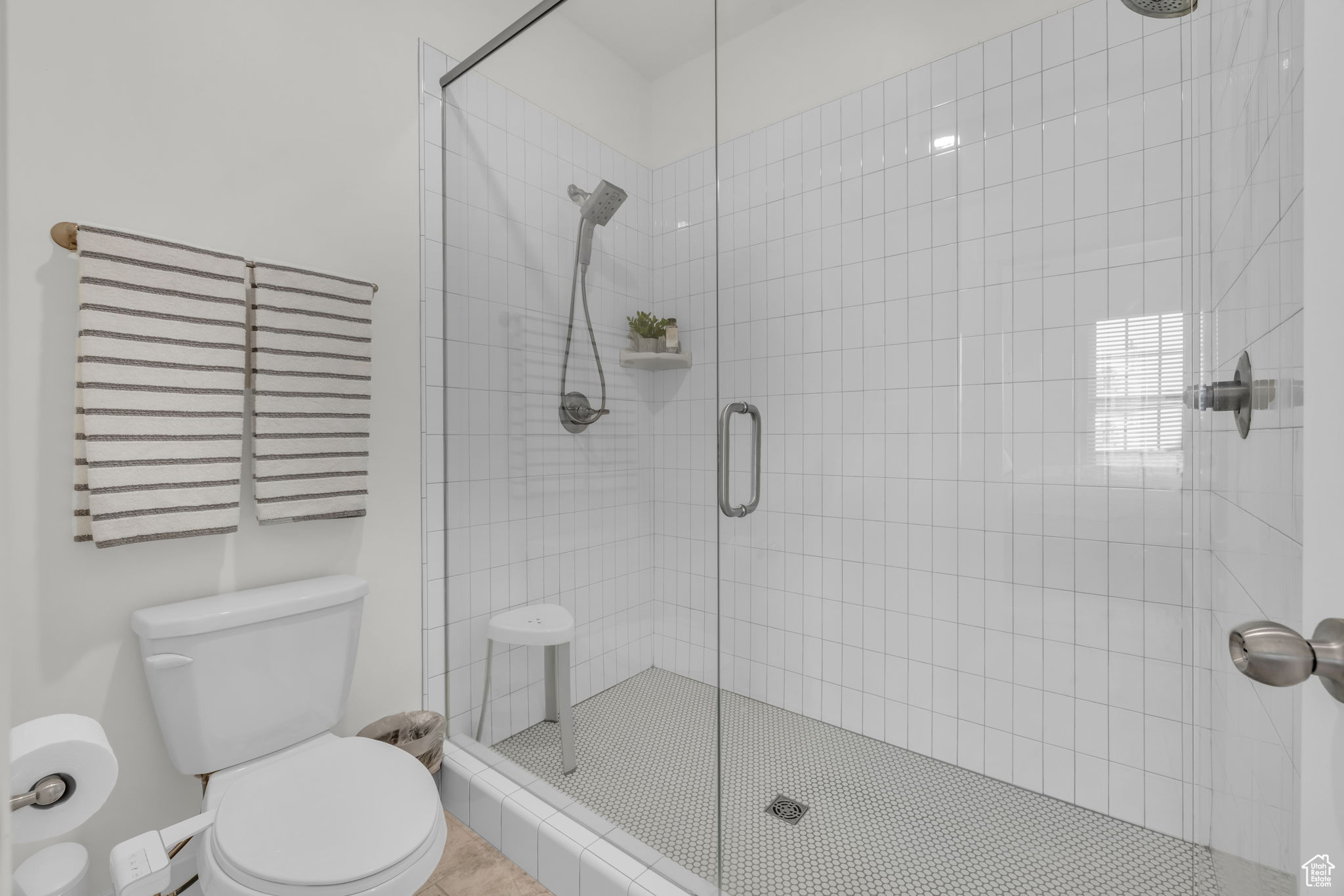 Bathroom featuring a shower with door, tile patterned floors, and toilet