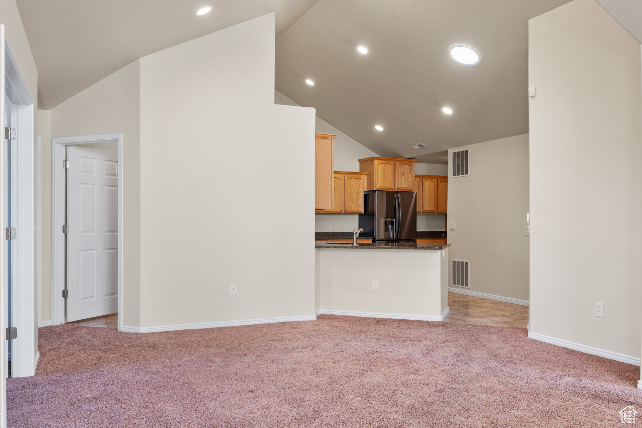 Unfurnished living room with light colored carpet and high vaulted ceiling