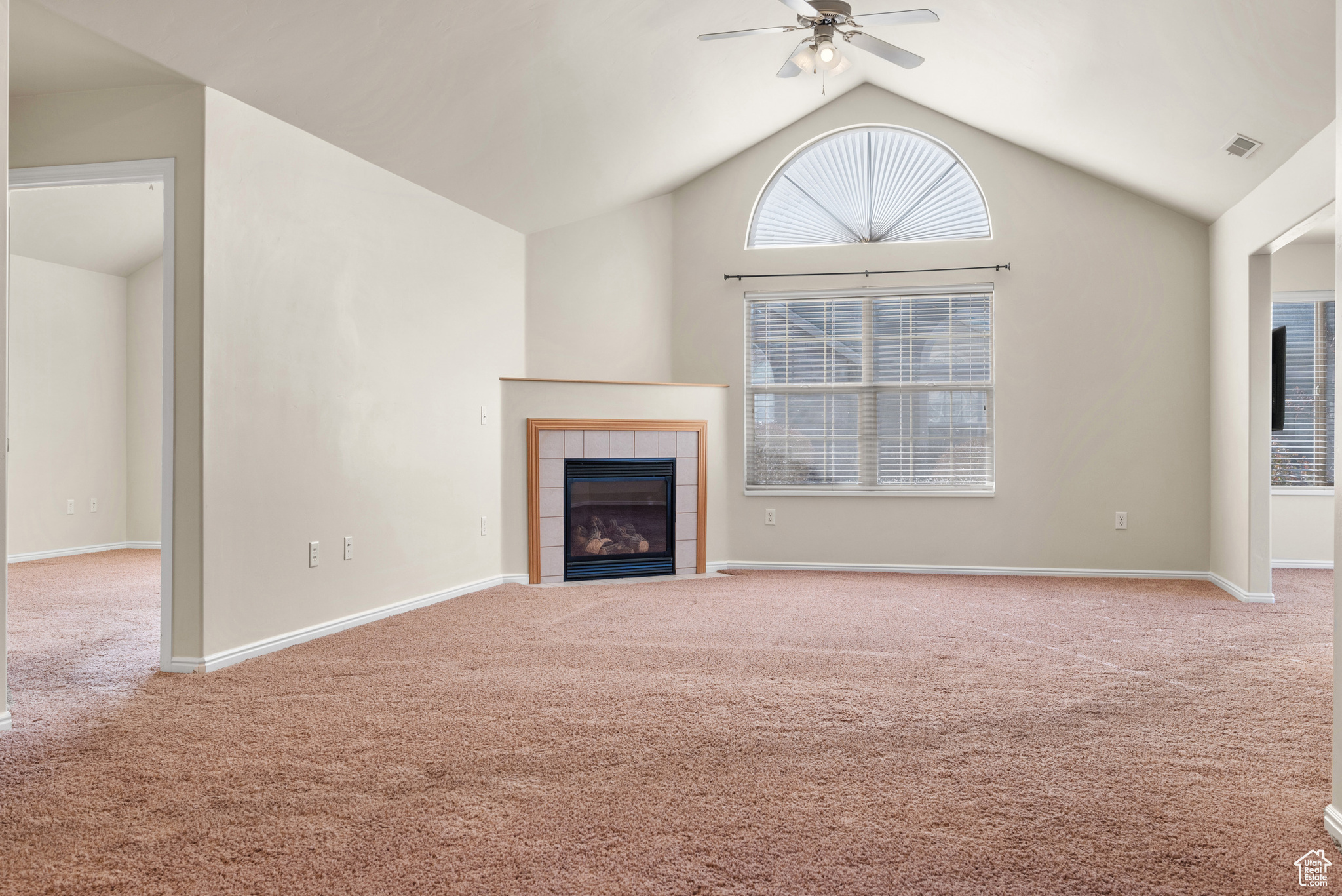 Unfurnished living room with a fireplace, carpet floors, high vaulted ceiling, and ceiling fan