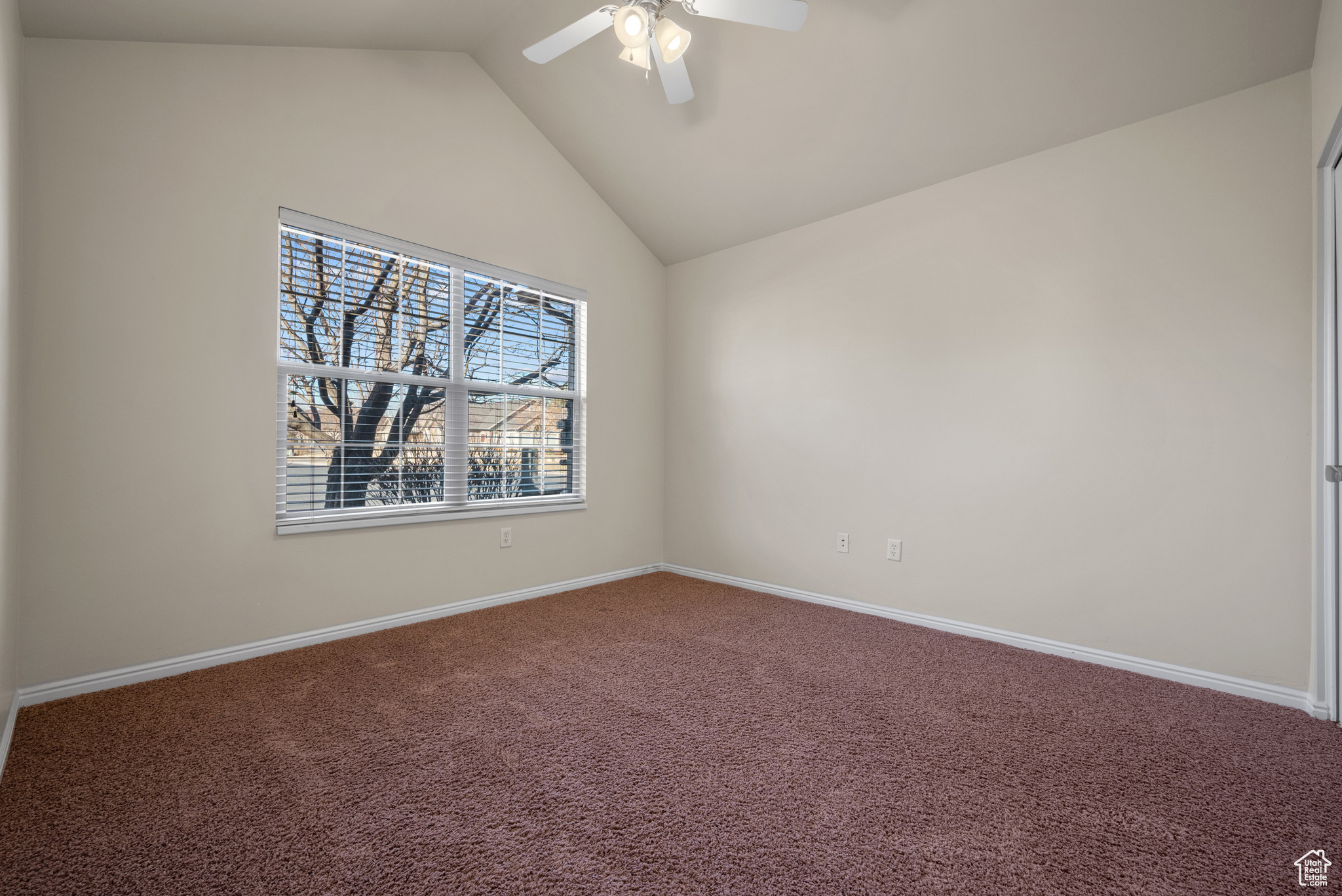 Spare room featuring ceiling fan, lofted ceiling, and carpet floors