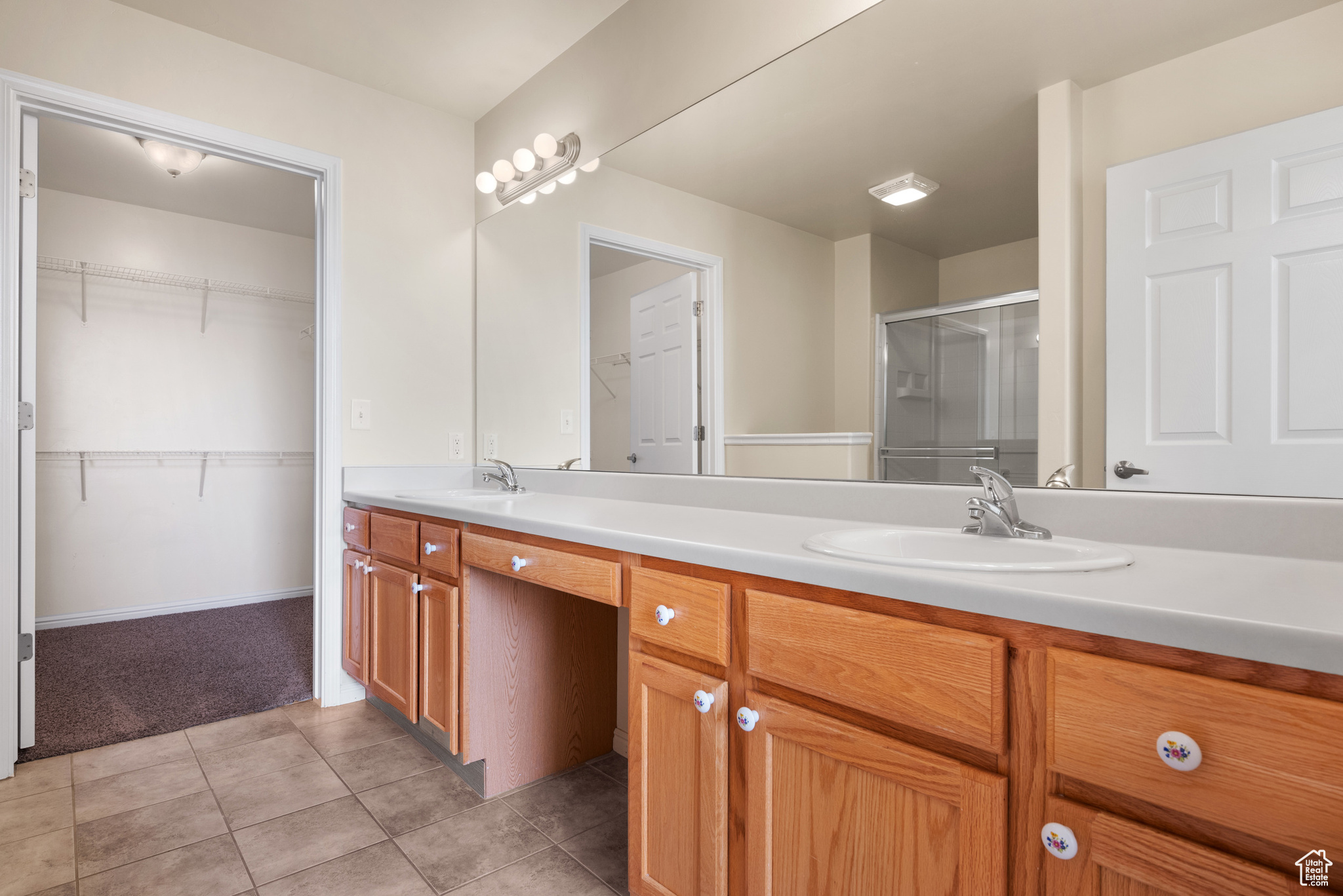 Bathroom with a shower with door, vanity, and tile patterned floors