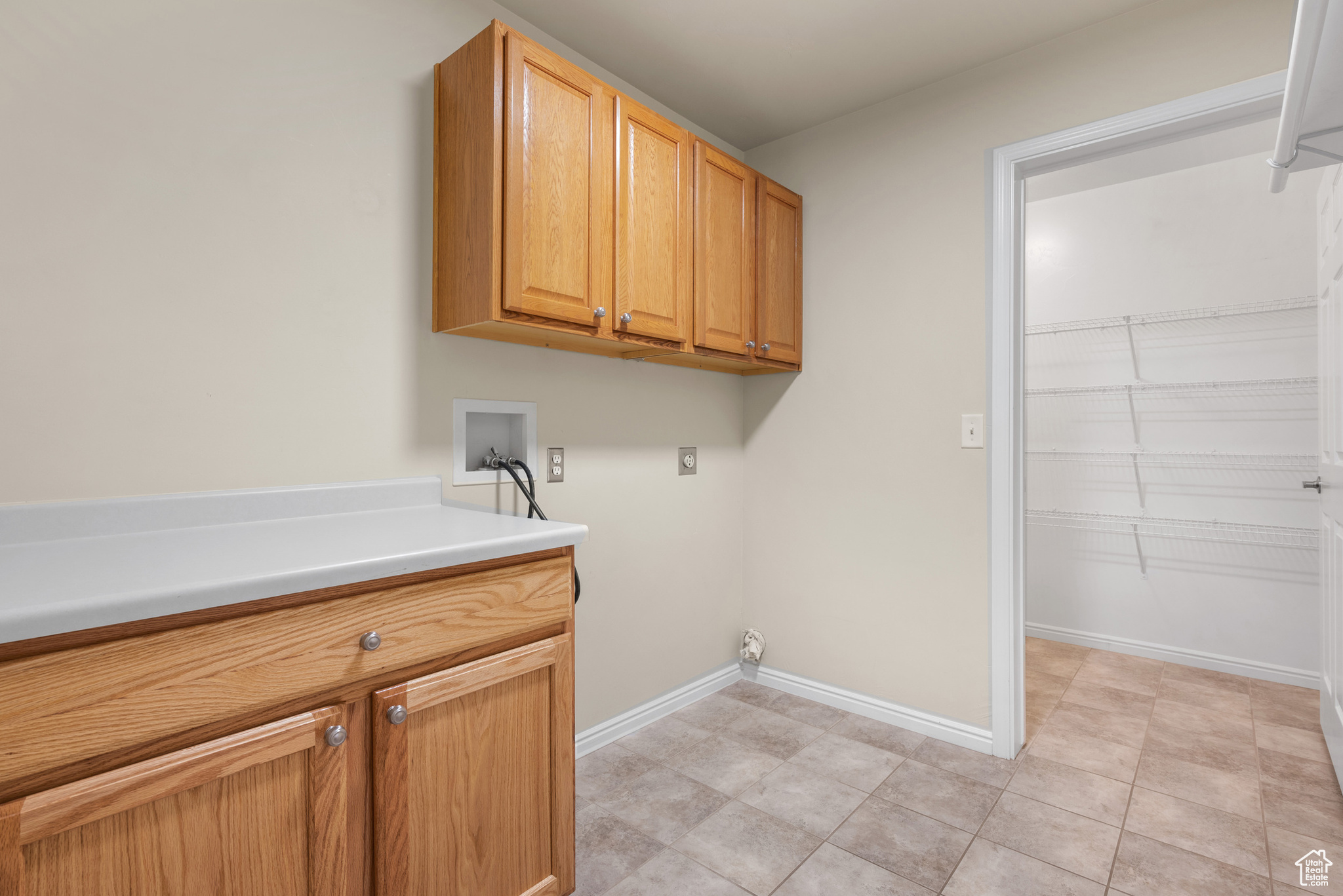 Washroom with cabinets, light tile patterned floors, hookup for a washing machine, and electric dryer hookup