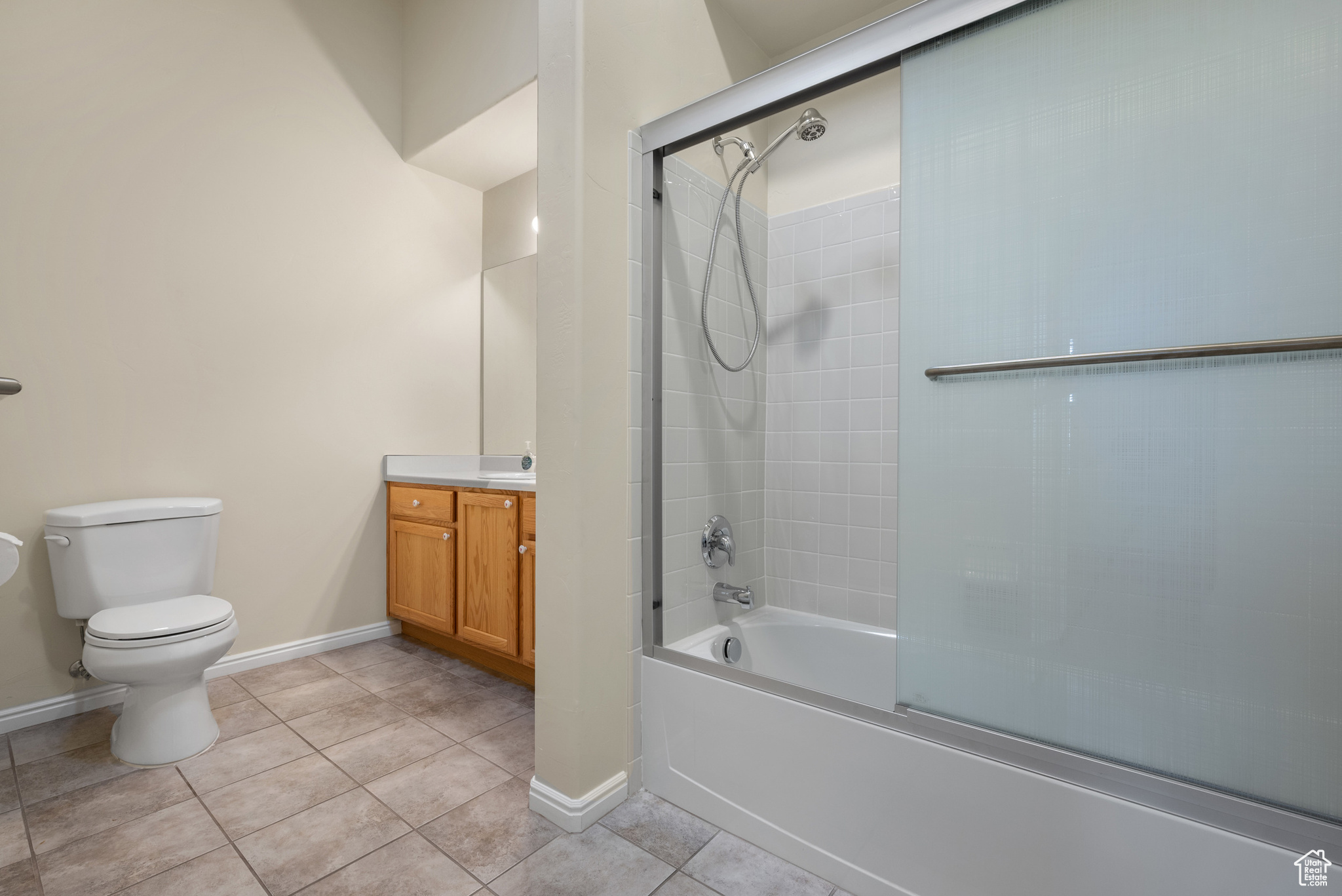 Full bathroom with enclosed tub / shower combo, vanity, toilet, and tile patterned flooring