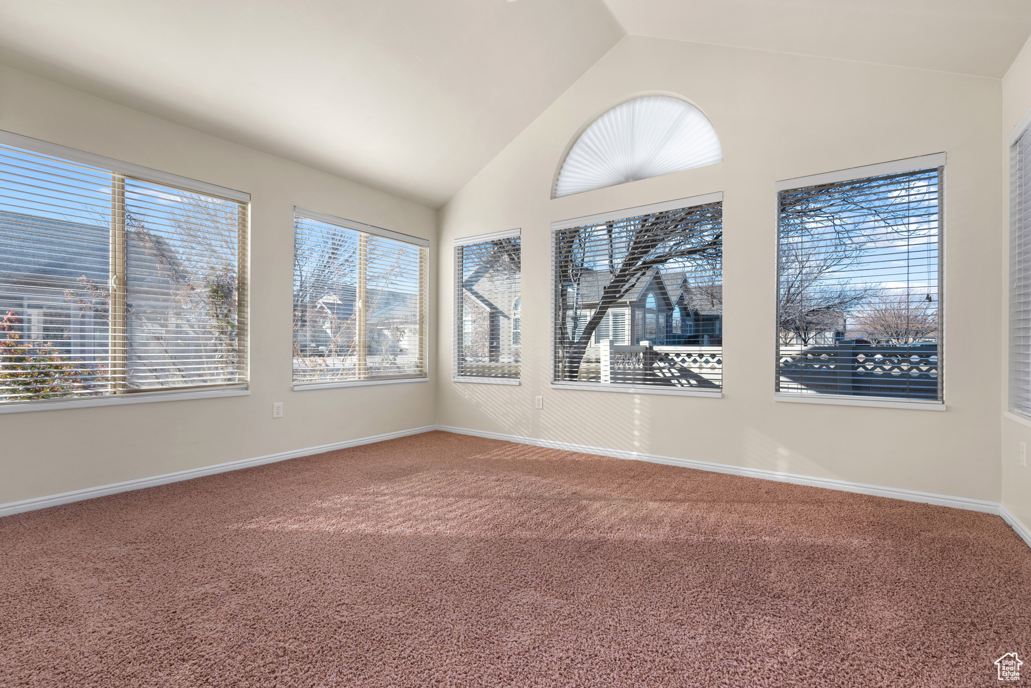 Carpeted spare room featuring vaulted ceiling