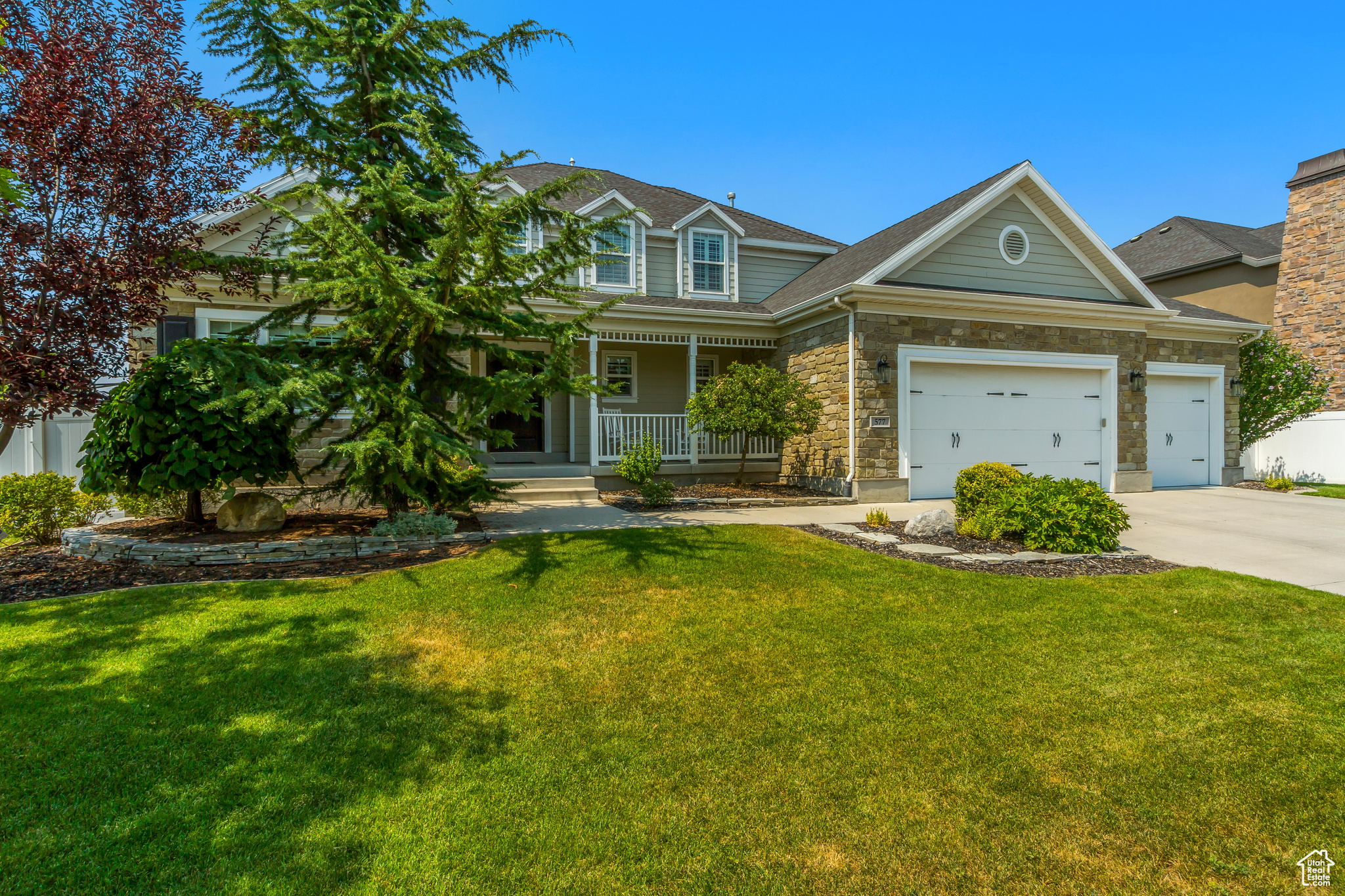 View of front of house with a garage, covered porch, and a front yard