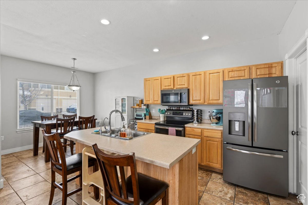 Kitchen featuring sink, a kitchen island with sink, stainless steel appliances, a kitchen breakfast bar, and light brown cabinets