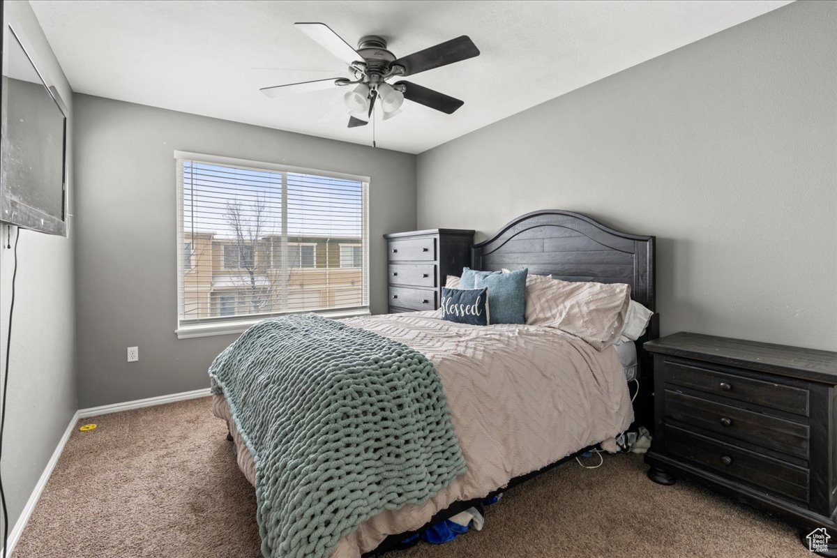 Carpeted bedroom featuring ceiling fan