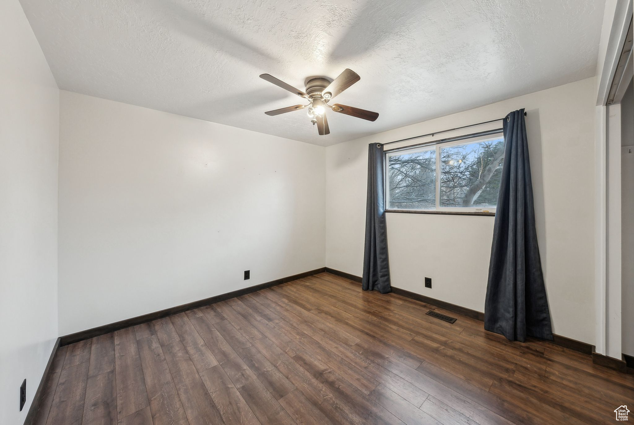 Unfurnished room featuring ceiling fan, dark hardwood / wood-style floors, and a textured ceiling