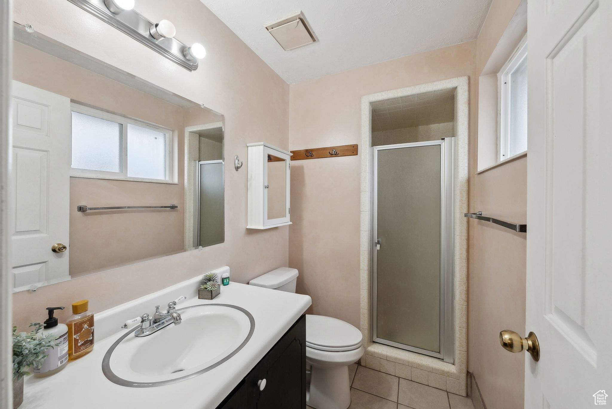 Bathroom with toilet, an enclosed shower, and tile patterned flooring