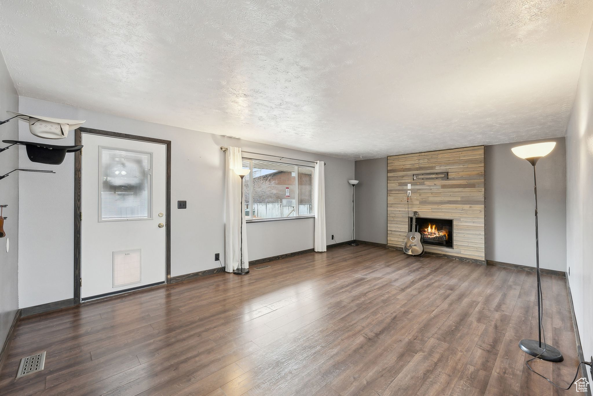 Unfurnished living room with a fireplace, dark hardwood / wood-style flooring, and a textured ceiling