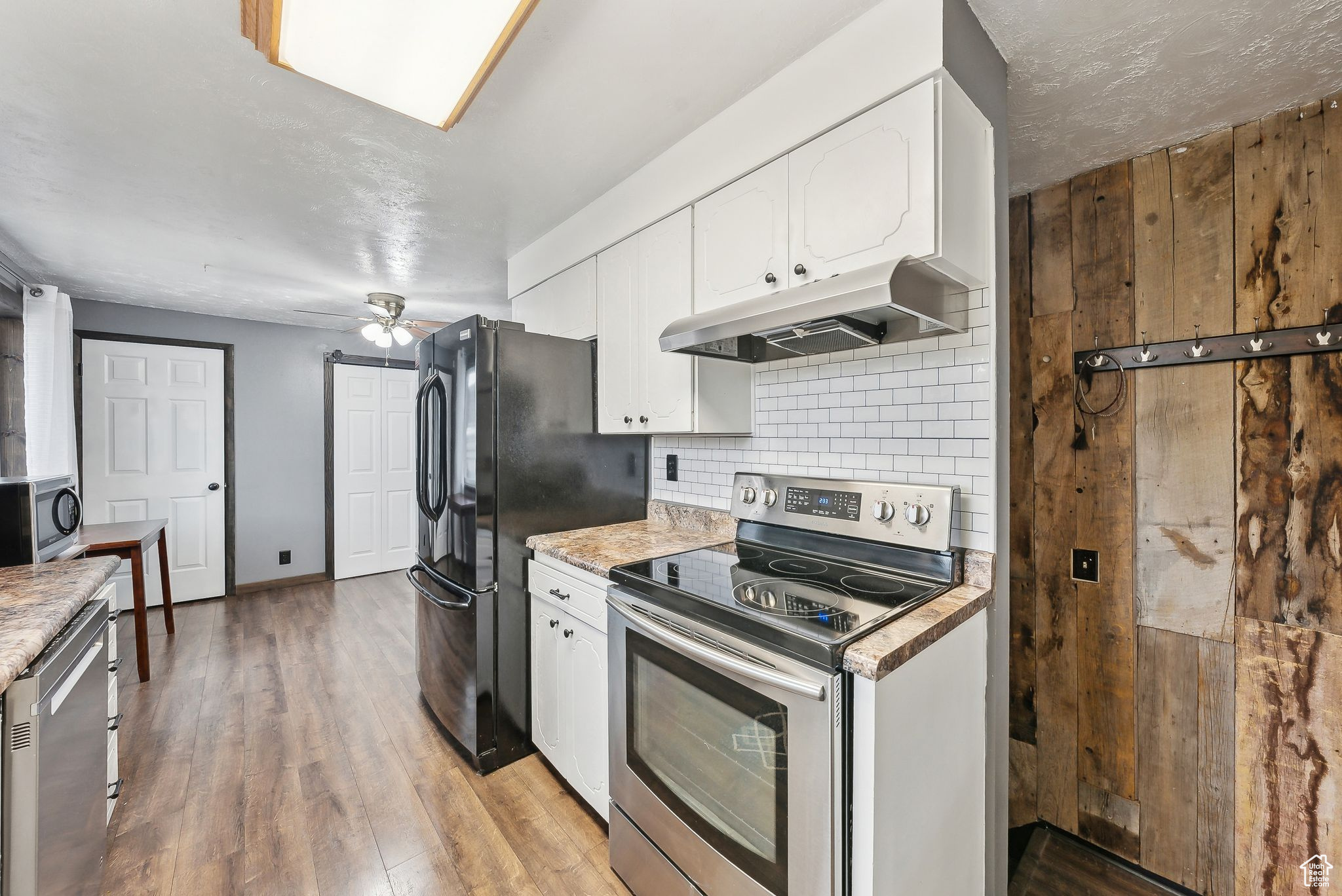 Kitchen featuring white cabinetry, appliances with stainless steel finishes, ceiling fan, light hardwood / wood-style floors, and backsplash