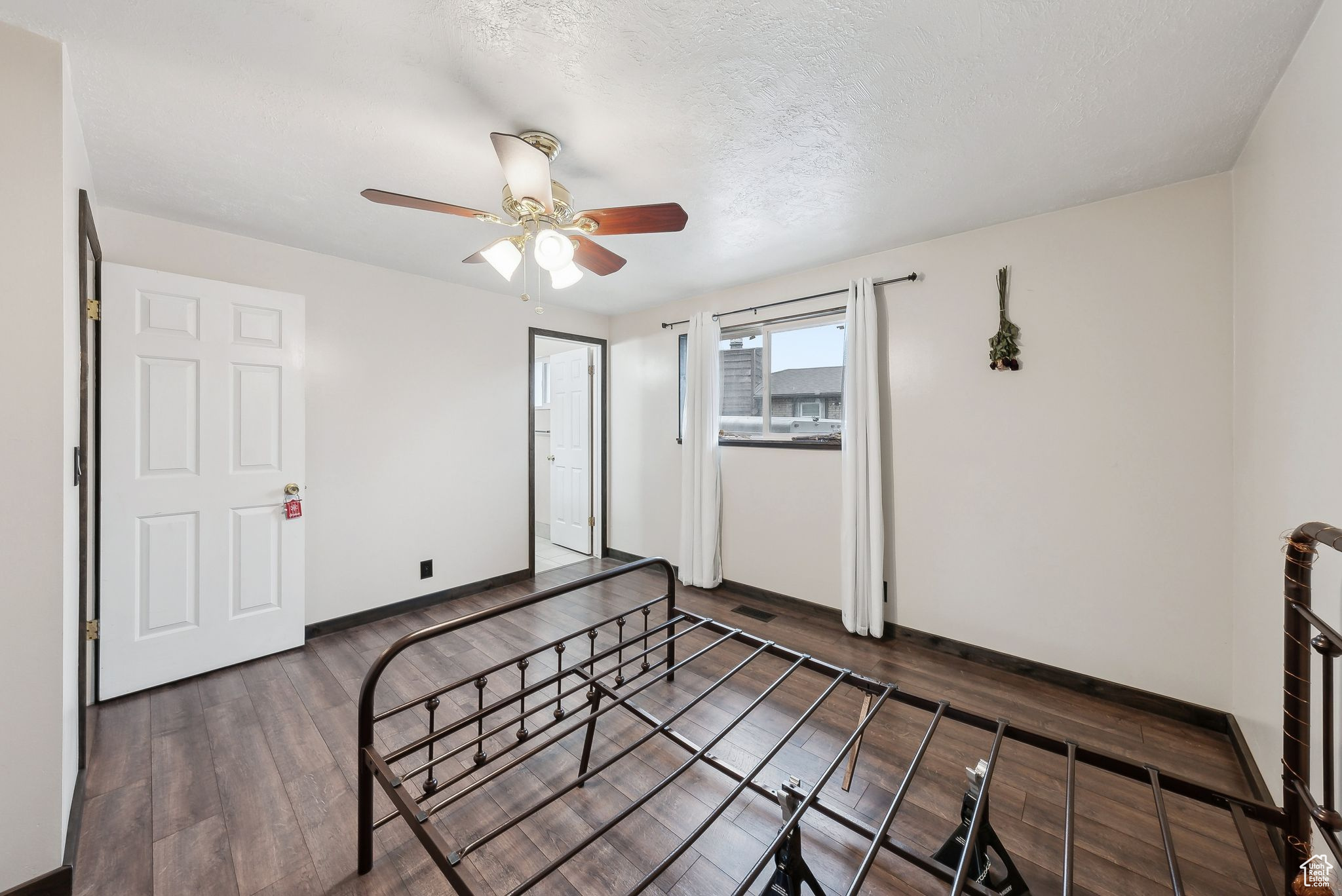 Bedroom featuring ceiling fan, dark hardwood / wood-style floors, and a textured ceiling