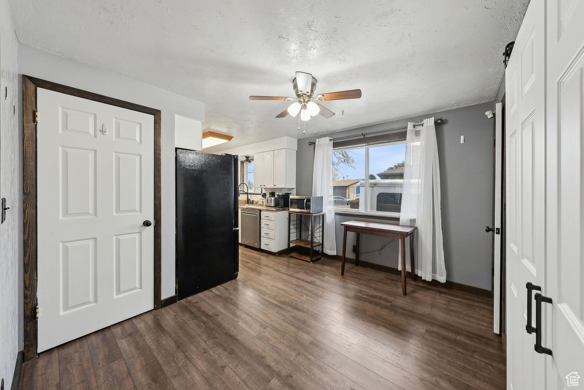 Kitchen with white cabinetry, ceiling fan, stainless steel appliances, and dark wood-type flooring