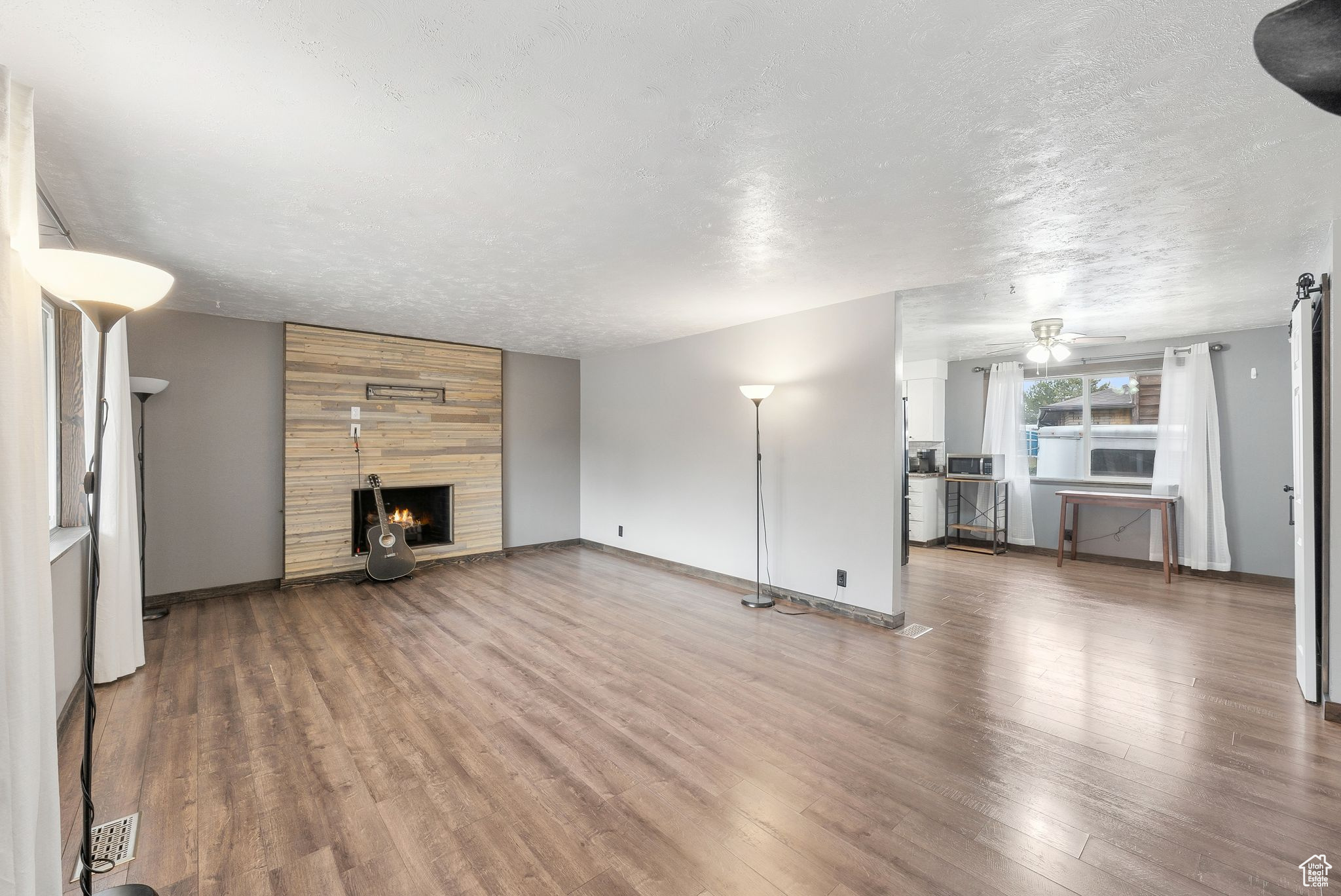 Unfurnished living room with hardwood / wood-style flooring, ceiling fan, a textured ceiling, and a fireplace