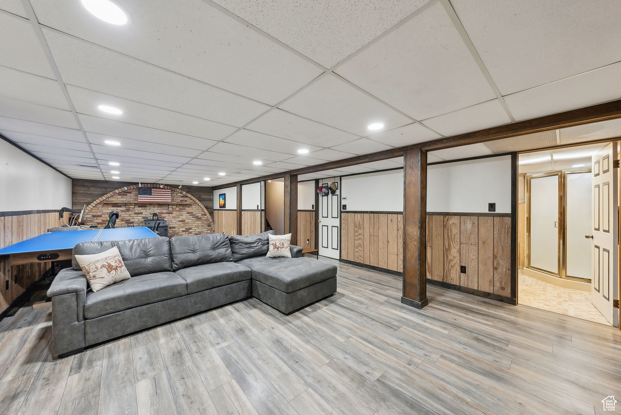 Living room with wood walls, light hardwood / wood-style flooring, and a drop ceiling