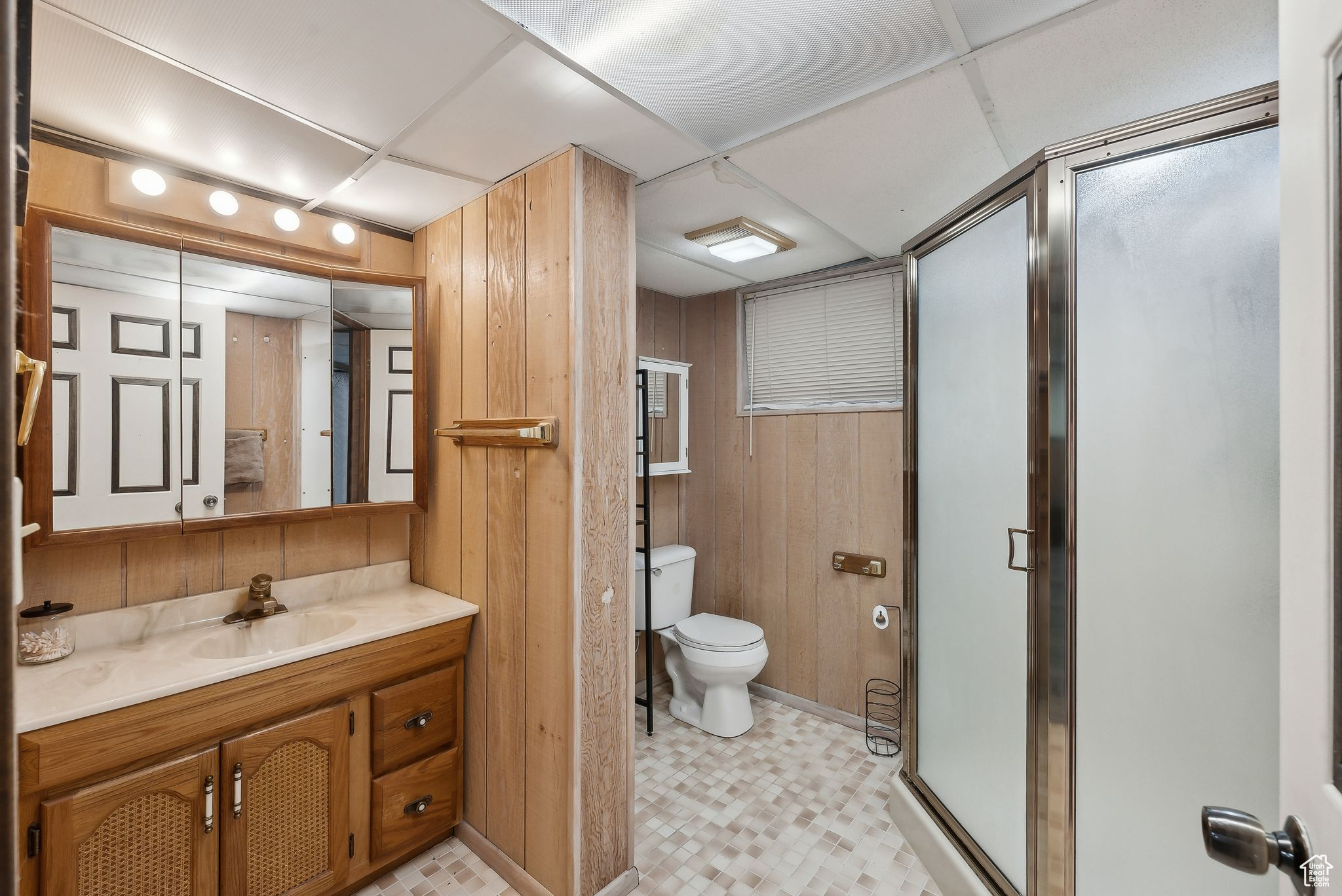 Bathroom featuring toilet, an enclosed shower, a paneled ceiling, vanity, and wooden walls