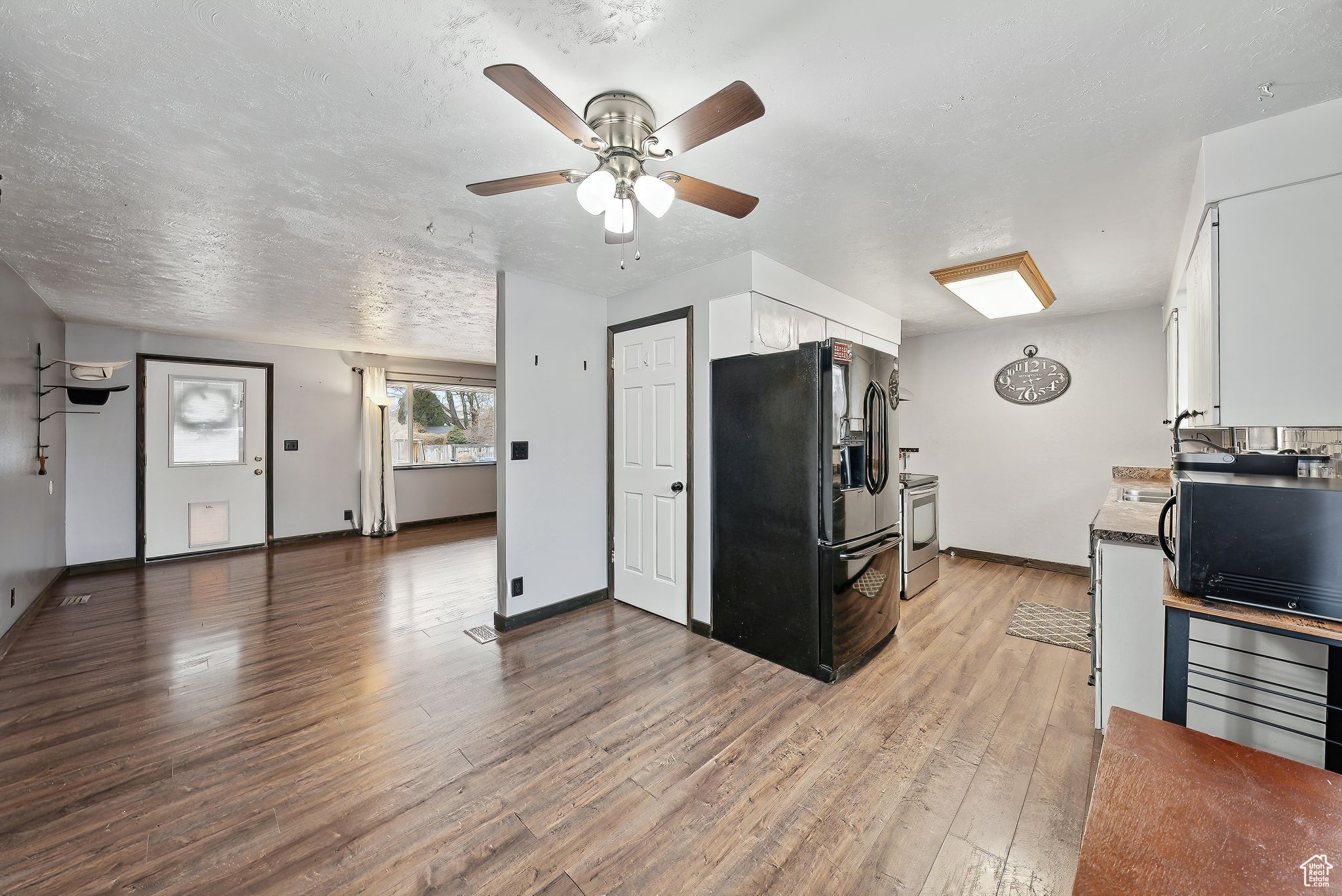 Kitchen featuring white cabinetry, hardwood / wood-style flooring, ceiling fan, black appliances, and a textured ceiling