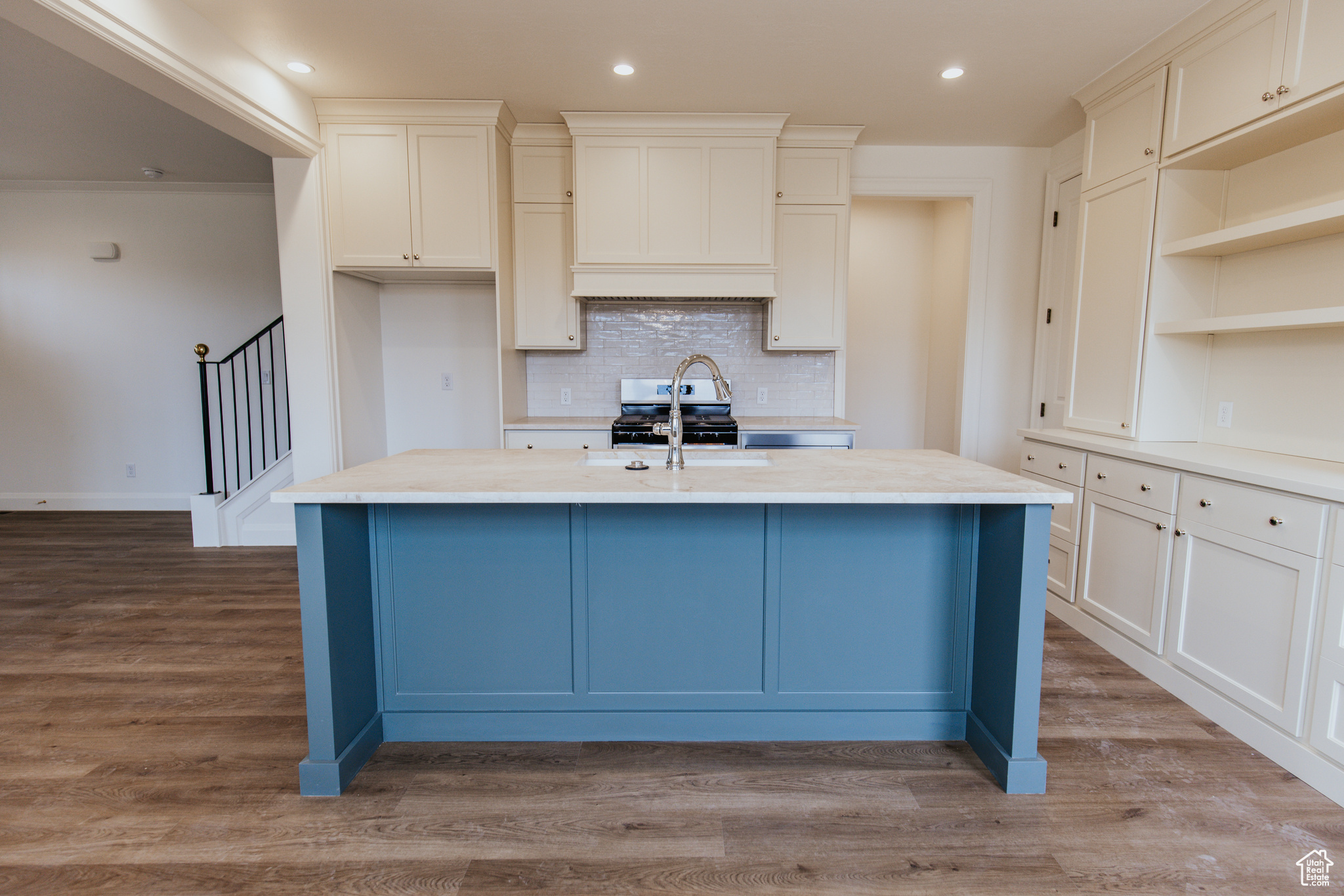 Kitchen featuring tasteful backsplash, a center island with sink, stainless steel range, and light wood-type flooring