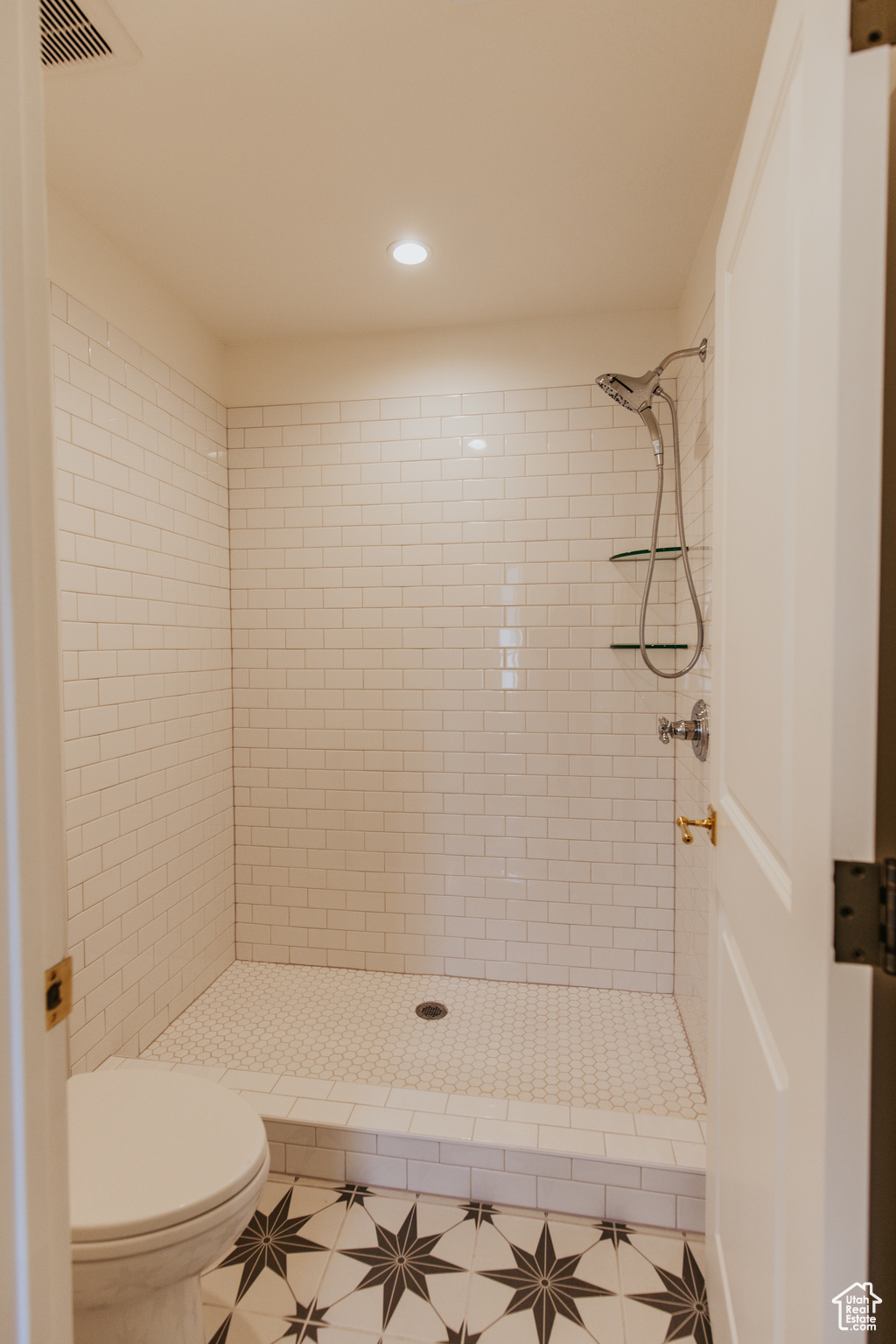 Bathroom featuring tiled shower, tile patterned floors, and toilet