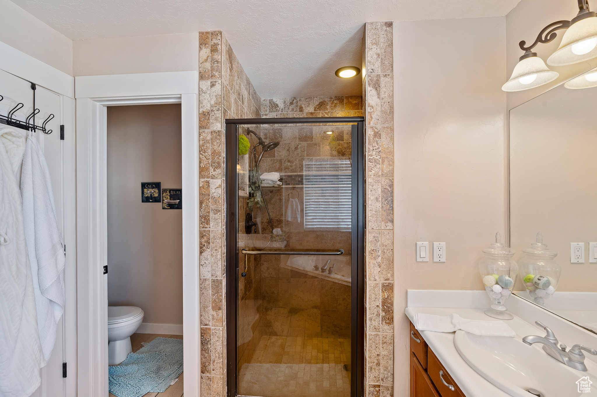 Bathroom with a shower with door, vanity, a textured ceiling, and toilet