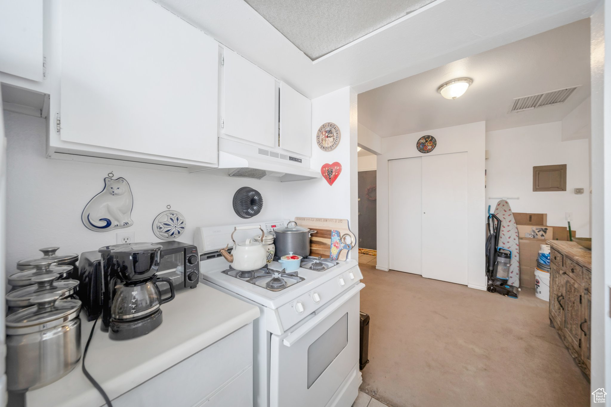 Kitchen featuring white cabinetry, light carpet, and gas range gas stove