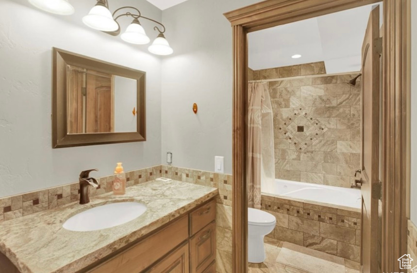 Full bathroom featuring vanity, shower / bathtub combination with curtain, and toilet