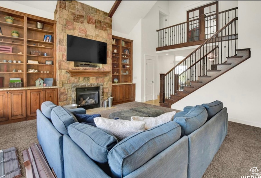 Carpeted living room with beamed ceiling, high vaulted ceiling, and a fireplace