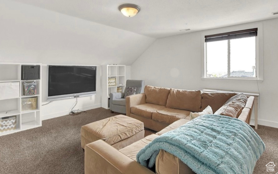 Living room with vaulted ceiling and dark colored carpet