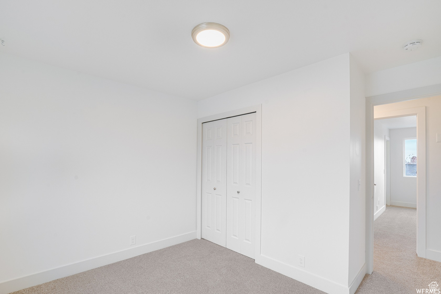 Unfurnished bedroom with light colored carpet and a closet