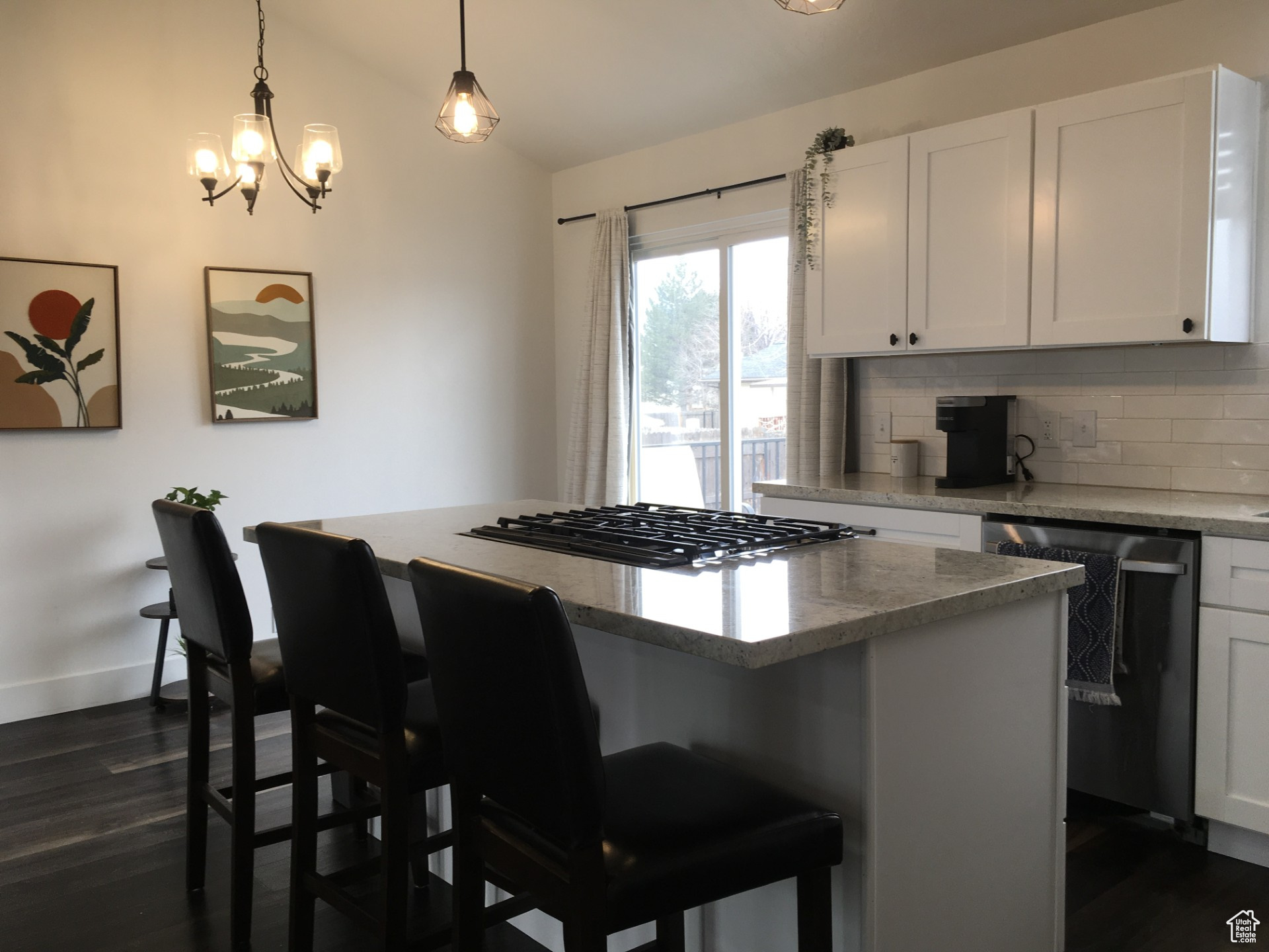 Kitchen featuring white cabinetry, a kitchen bar, black dishwasher, and a kitchen island