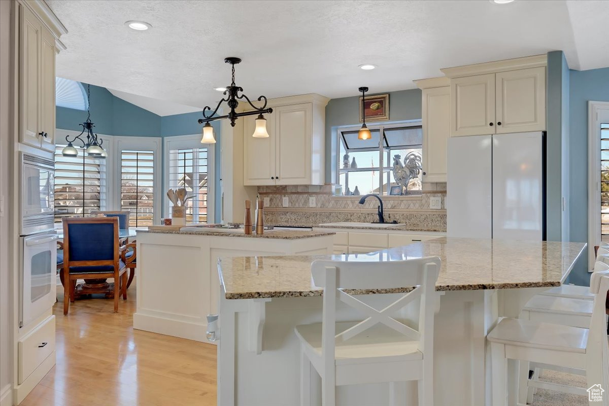 Kitchen featuring tasteful backsplash, a kitchen bar, sink, and white appliances