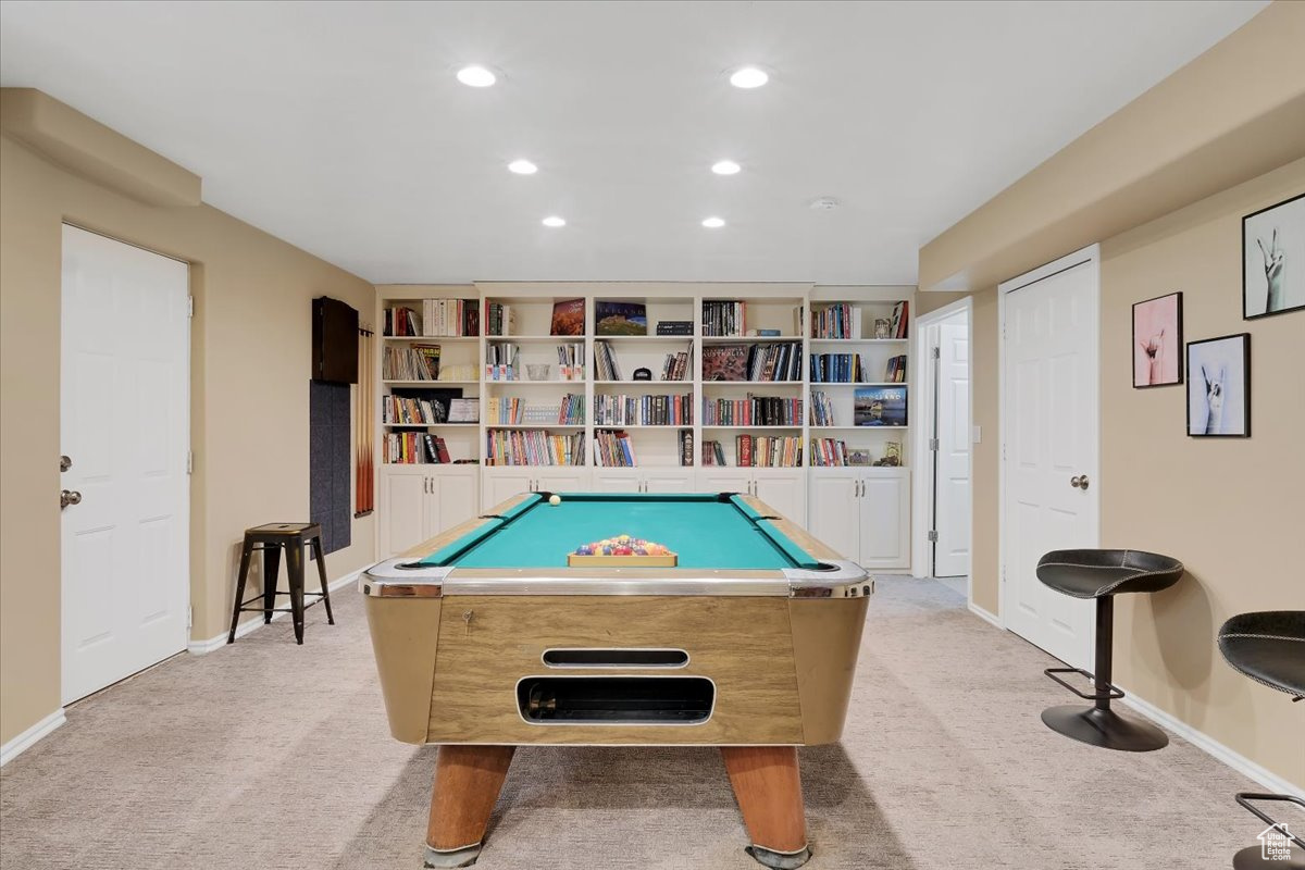 Open space with pool table and light carpet and built-in shelving and walk-out door