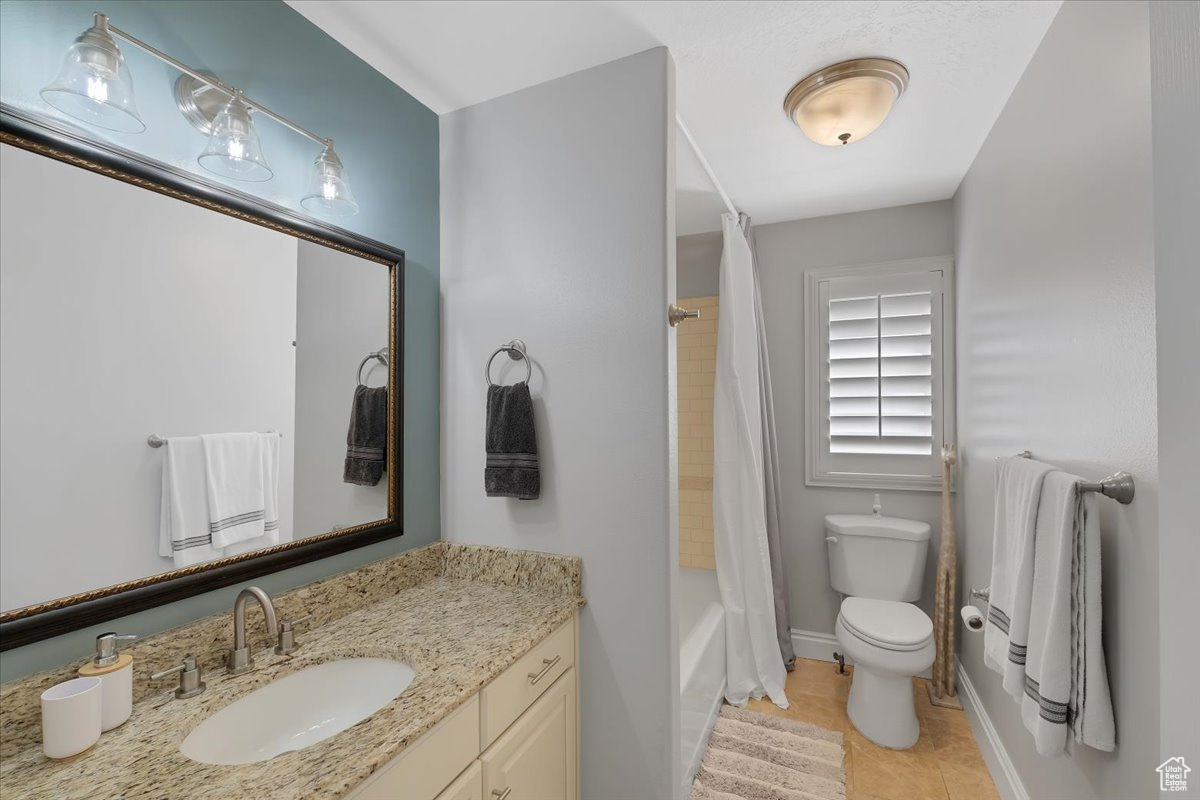 Full bathroom featuring vanity, toilet, tile patterned flooring, and shower / bath combo with shower curtain