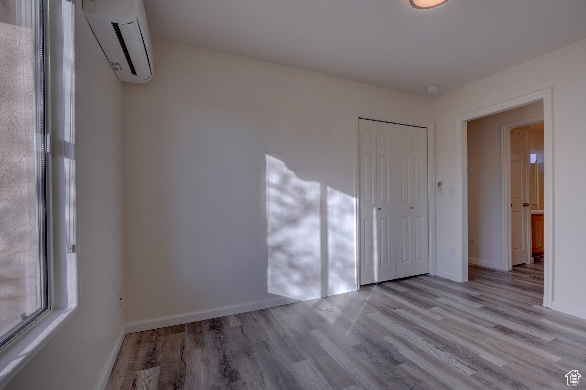 Unfurnished room featuring a wall mounted air conditioner and light wood-type flooring