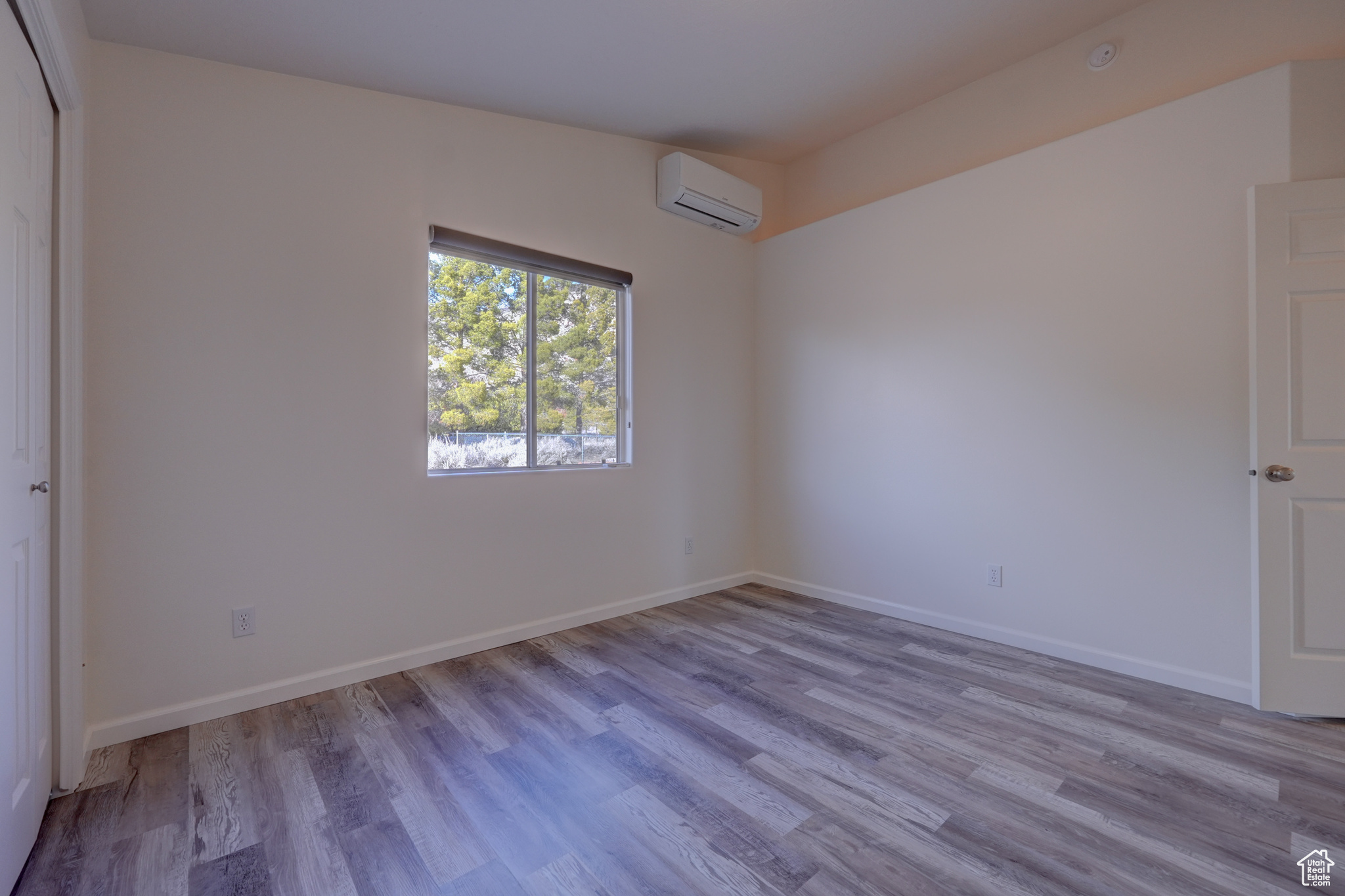 Unfurnished room with light hardwood / wood-style flooring and a wall mounted AC