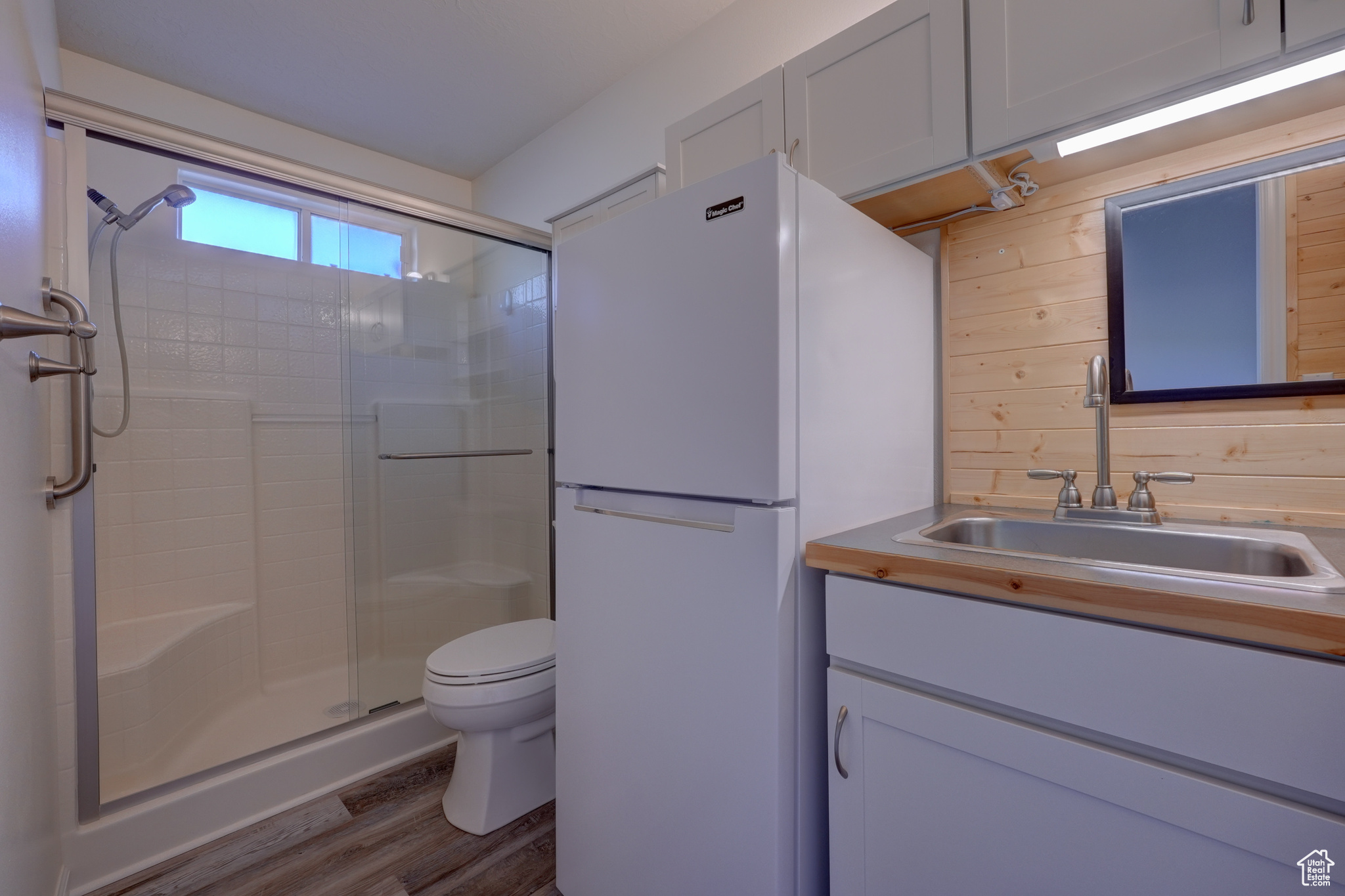 Bathroom featuring toilet, an enclosed shower, vanity, wooden walls, and hardwood / wood-style floors