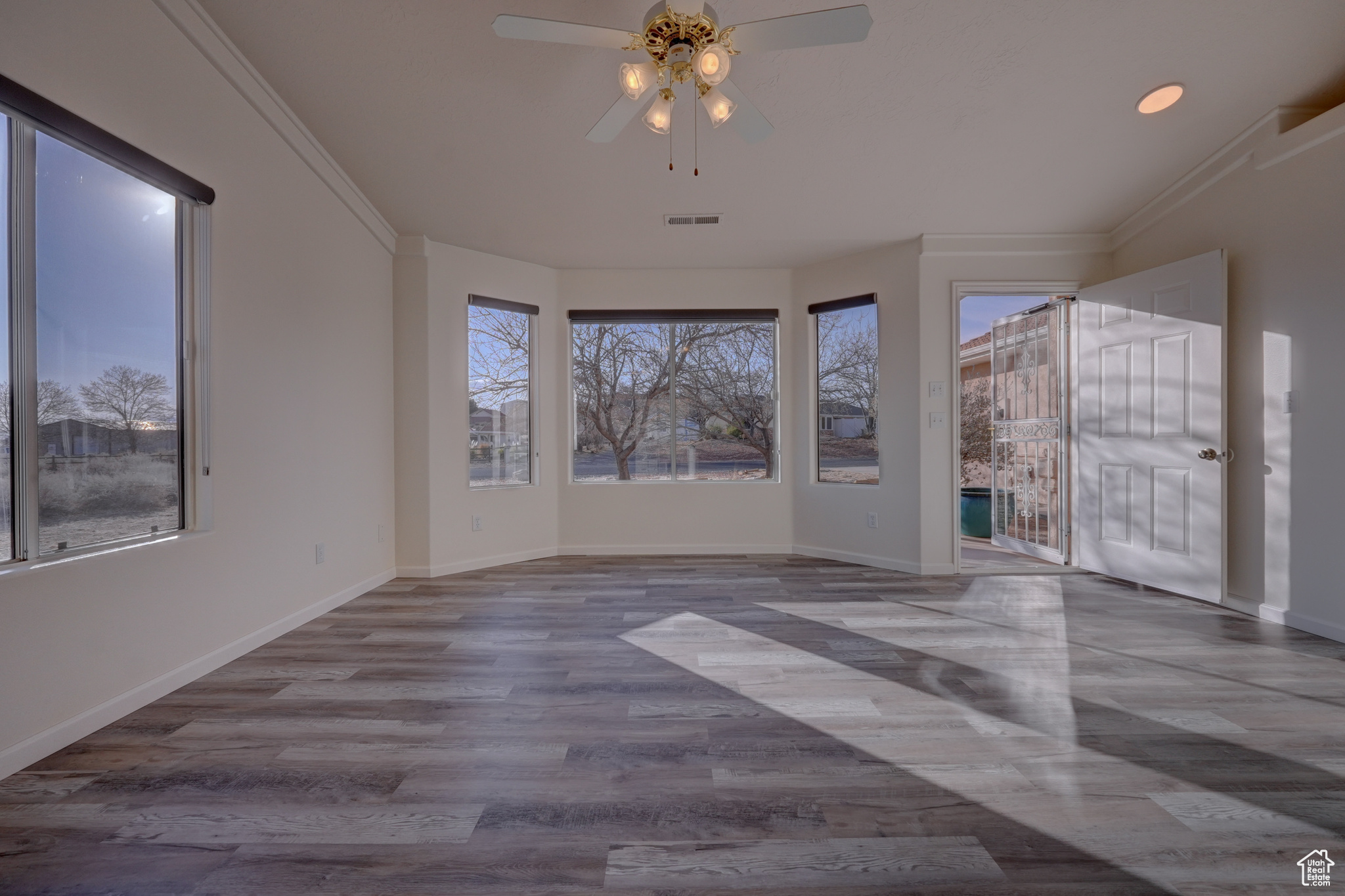 Unfurnished room featuring crown molding, ceiling fan, and a wealth of natural light