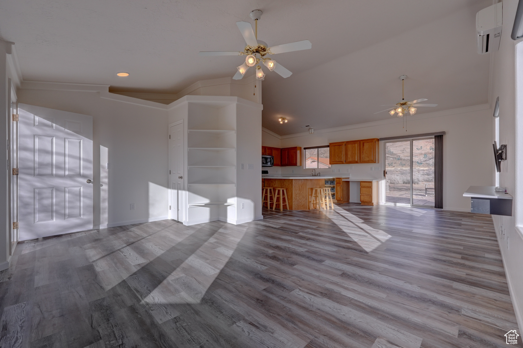 Unfurnished living room featuring ornamental molding, lofted ceiling, ceiling fan, and light hardwood / wood-style floors