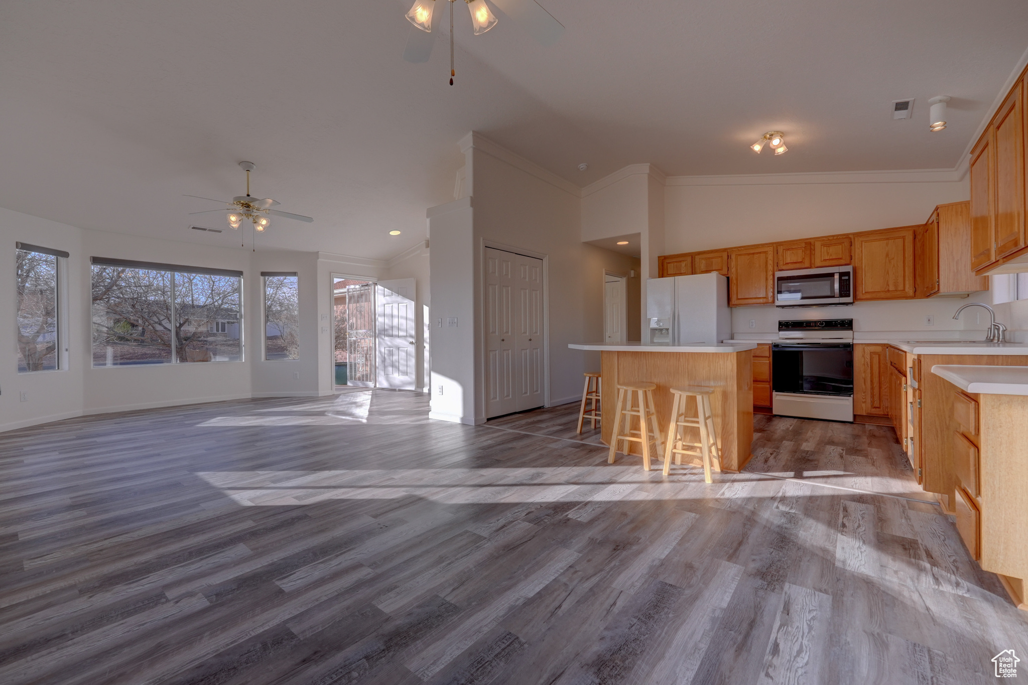 Kitchen featuring white appliances, vaulted ceiling, light hardwood / wood-style floors, and a center island
