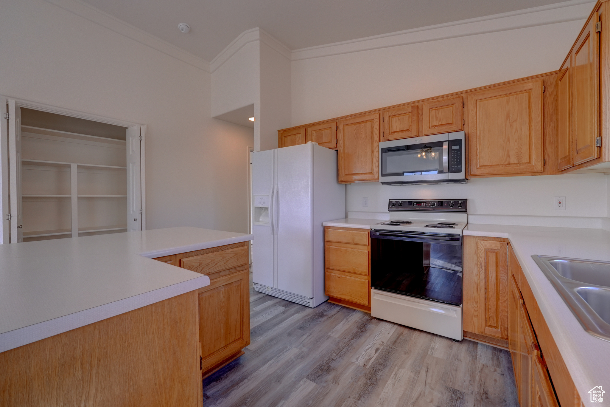 Kitchen featuring light brown cabinetry, sink, crown molding, white appliances, and light hardwood / wood-style flooring