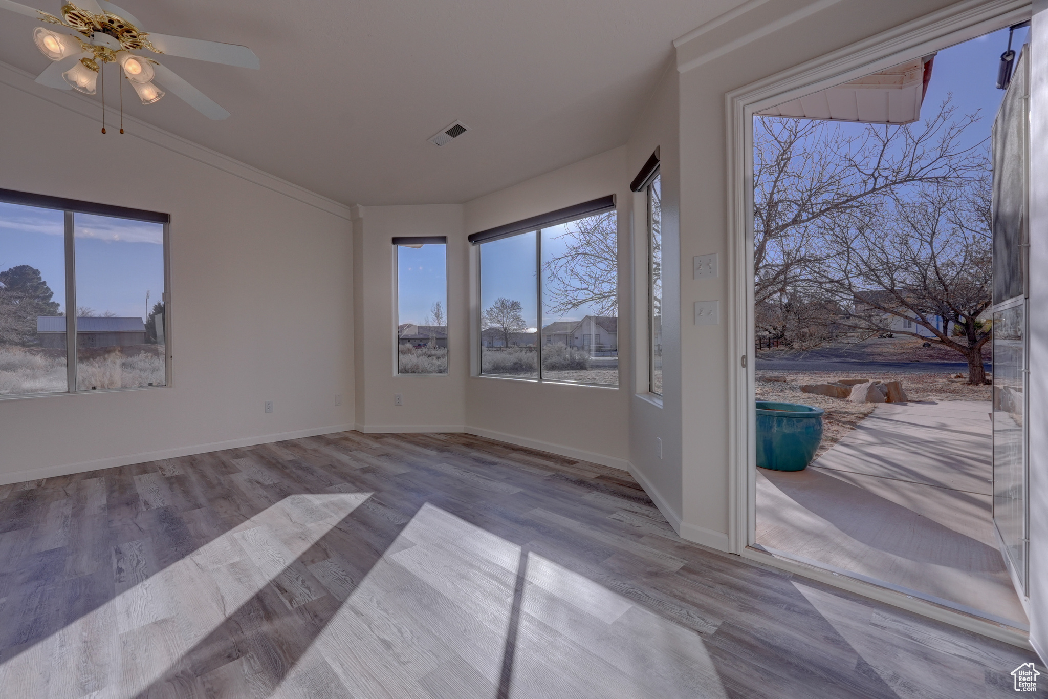 Interior space with crown molding, ceiling fan, and light wood-type flooring