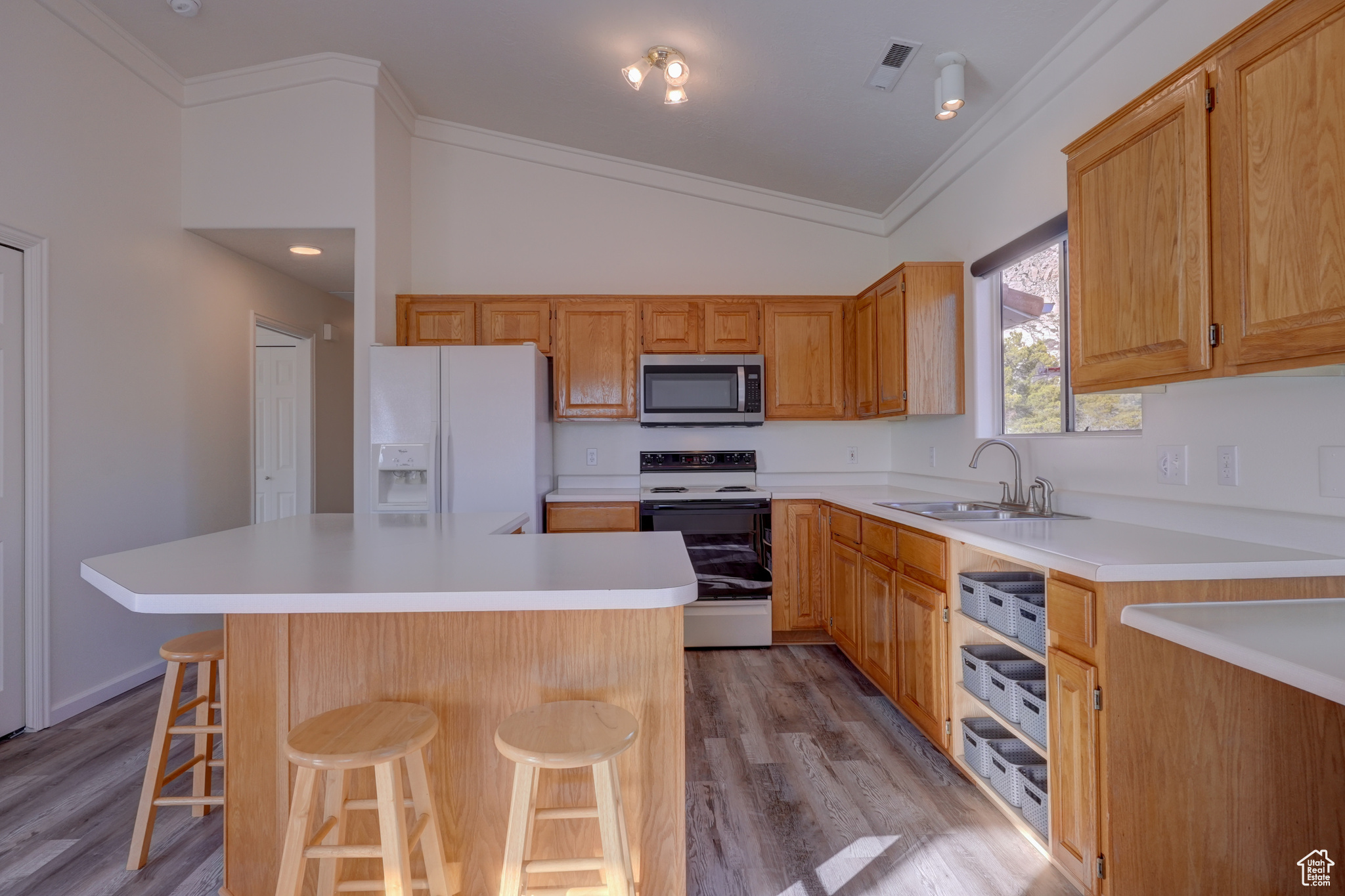 Kitchen featuring vaulted ceiling, a breakfast bar, sink, a center island, and white appliances