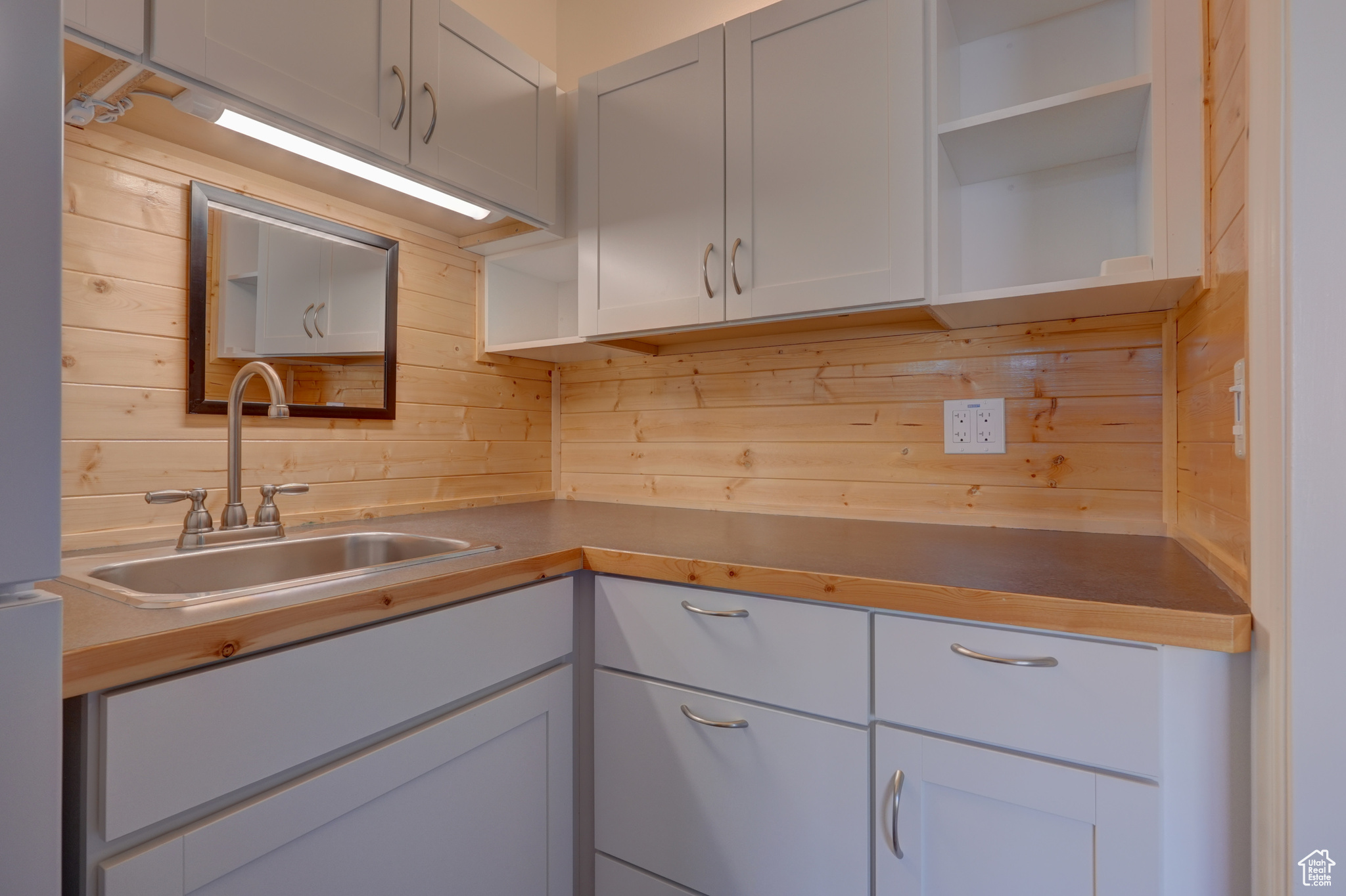 Kitchen with sink, backsplash, and wood walls