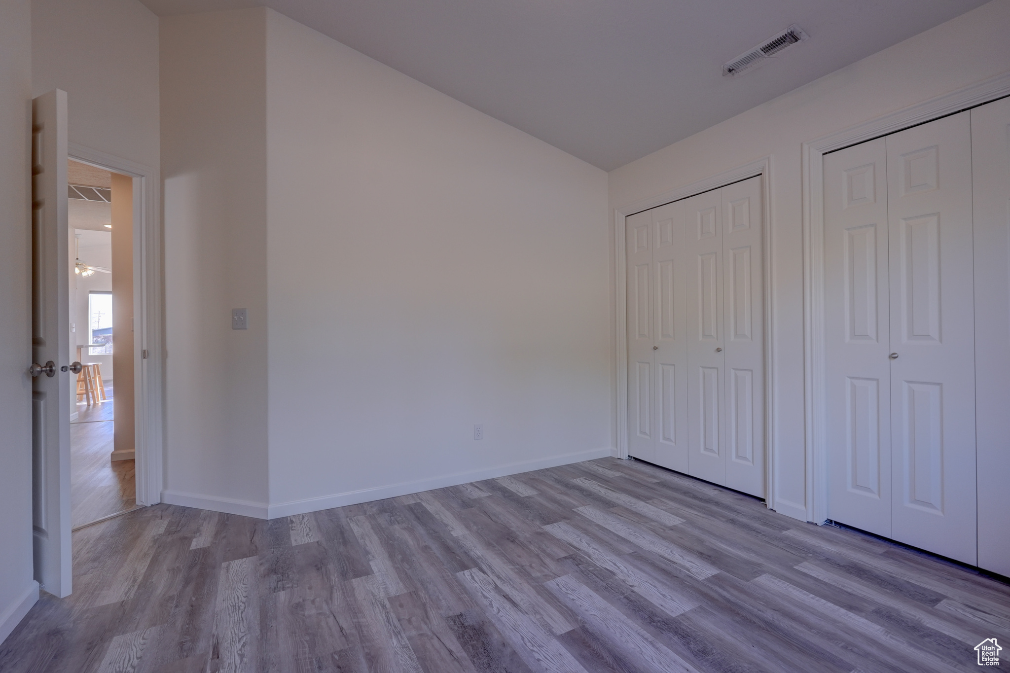 Unfurnished bedroom with light hardwood / wood-style flooring and two closets
