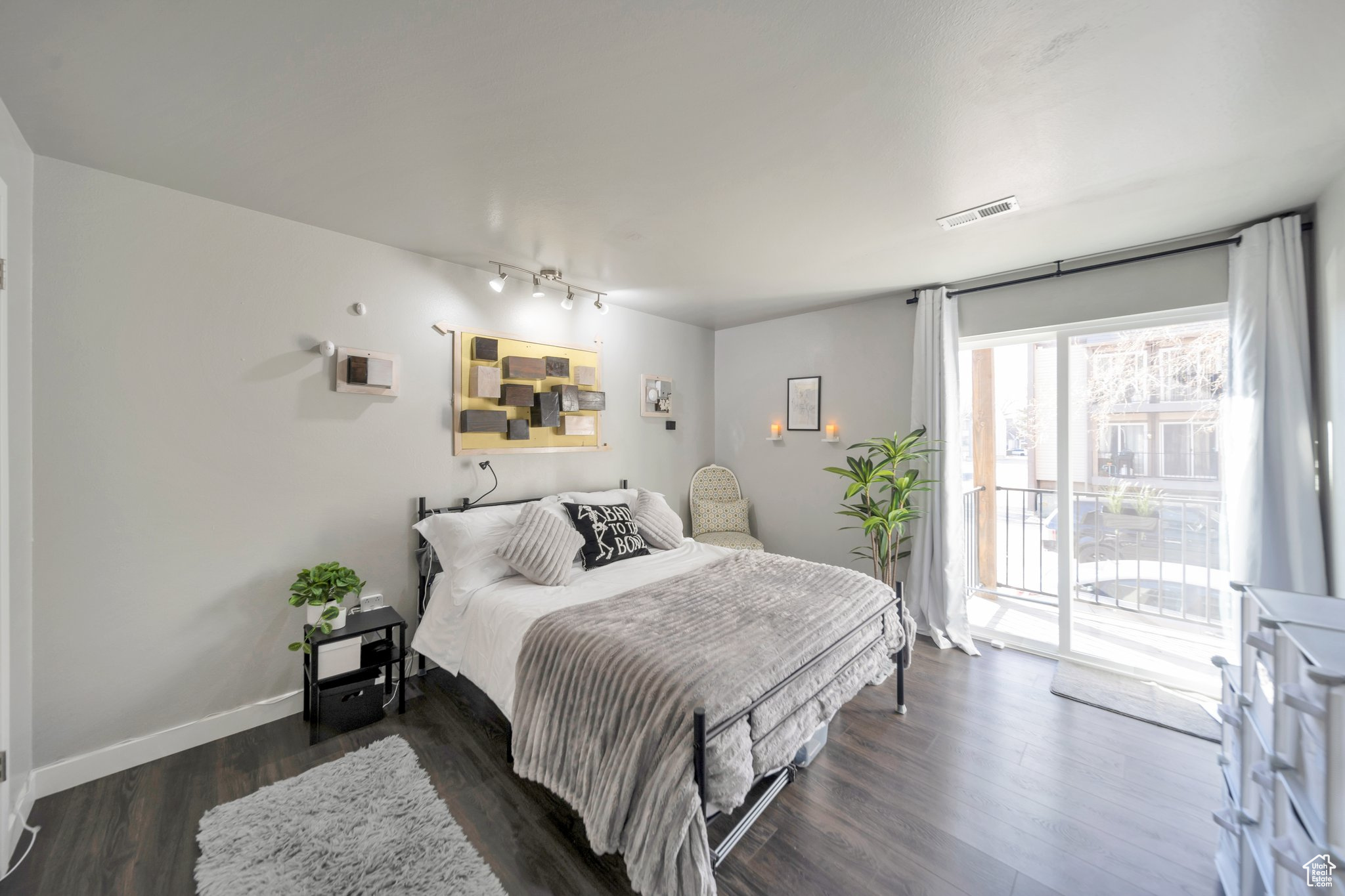 Bedroom with dark hardwood / wood-style flooring, access to exterior, and track lighting